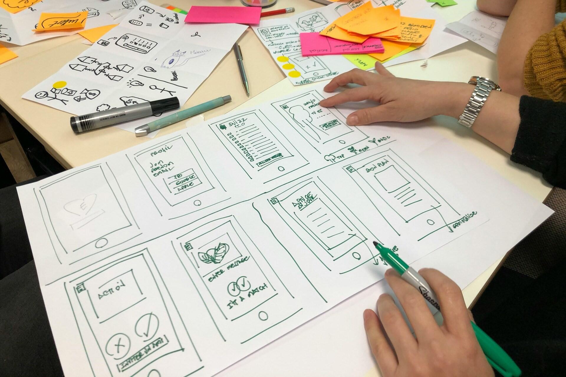 UI designer sketching mobile wireframes during the early planning stage of an app design