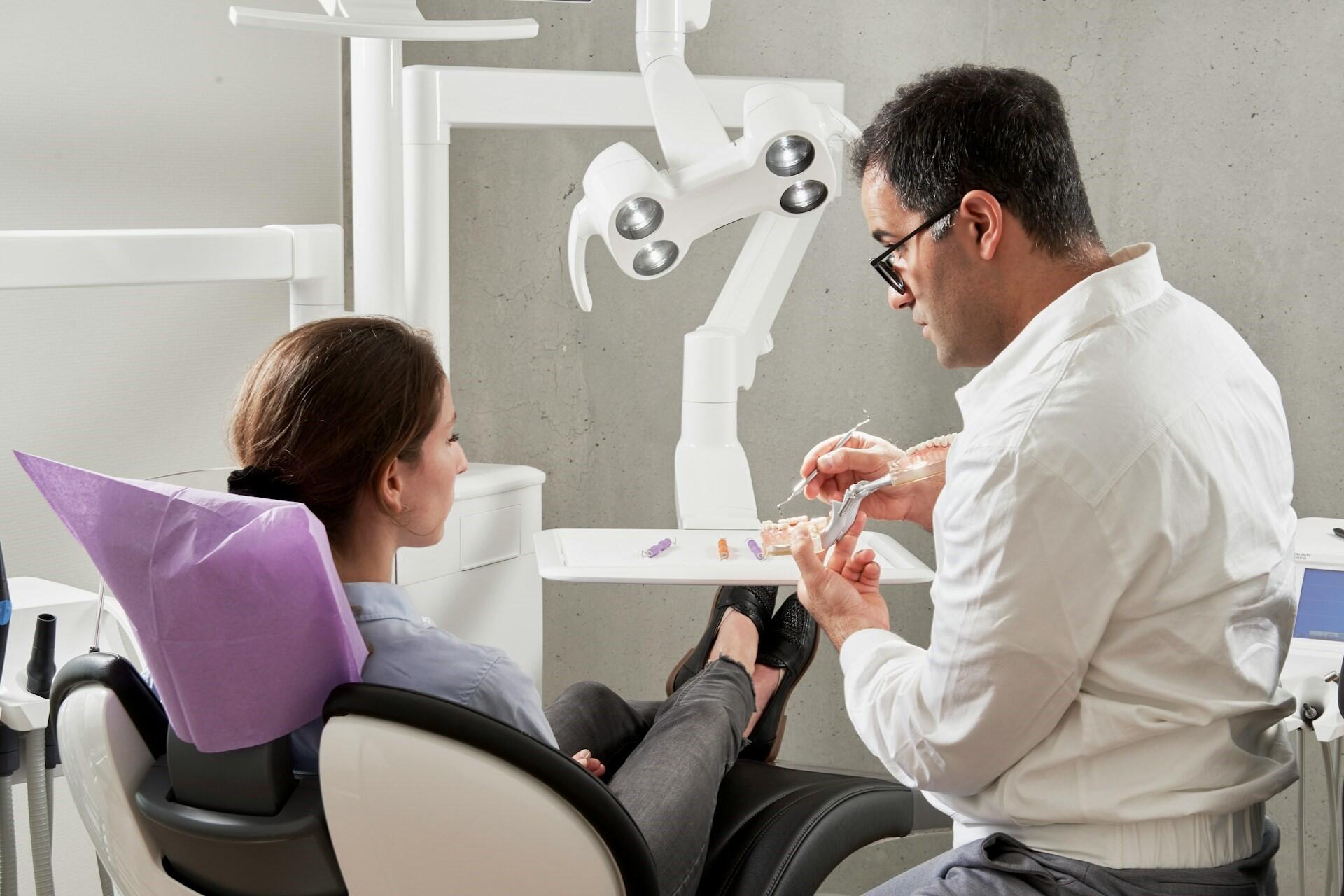 Dentist showing a dental model to a patient in a dental chair