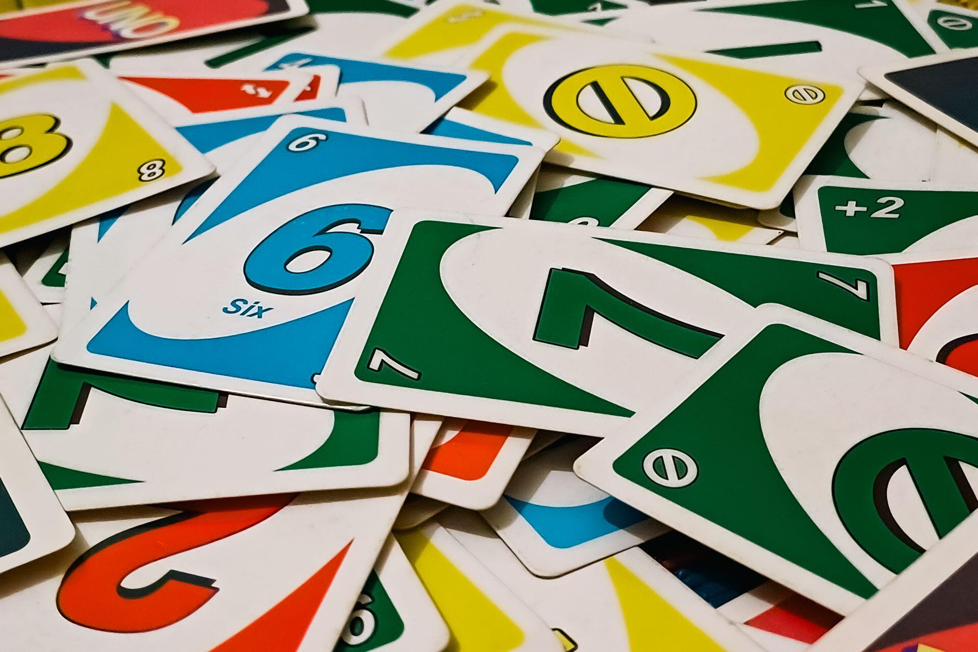 Pile of colorful Uno cards scattered, showing various numbers and action symbols in green, blue, yellow, and red colors.