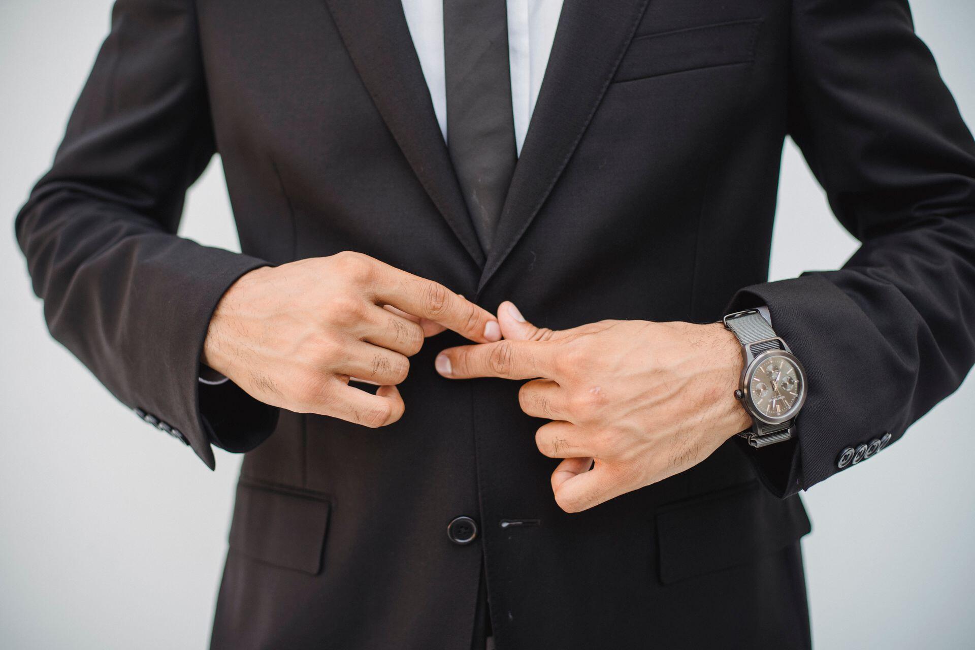 Man buttoning up black suit