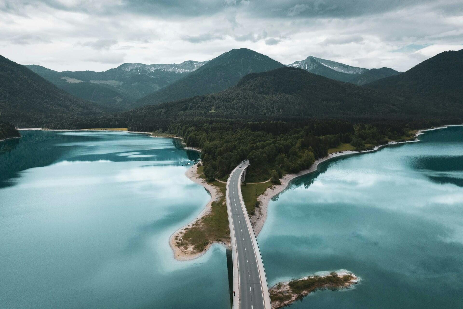 Road crossing turquoise alpine lakes and forested mountains