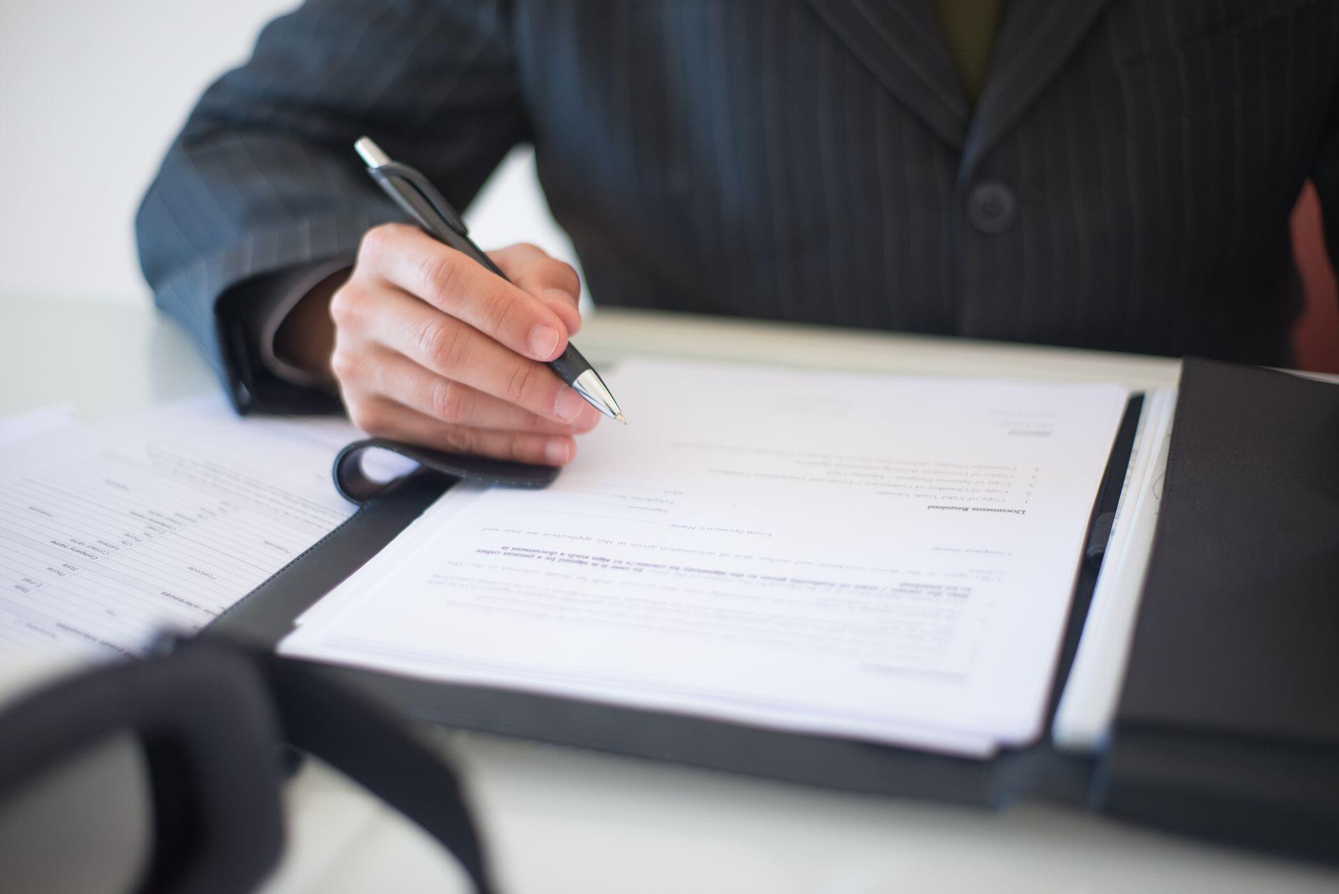 image of a hand holding a pen and a document inside a folder