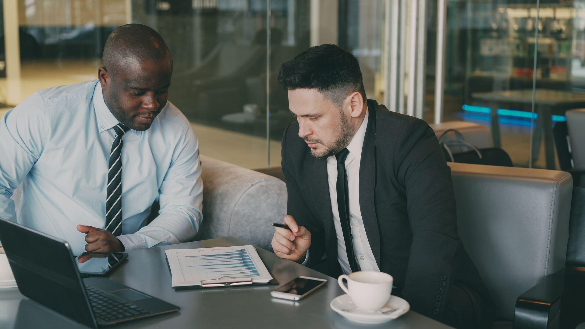 Image of two businessmen sat at a table with coffee