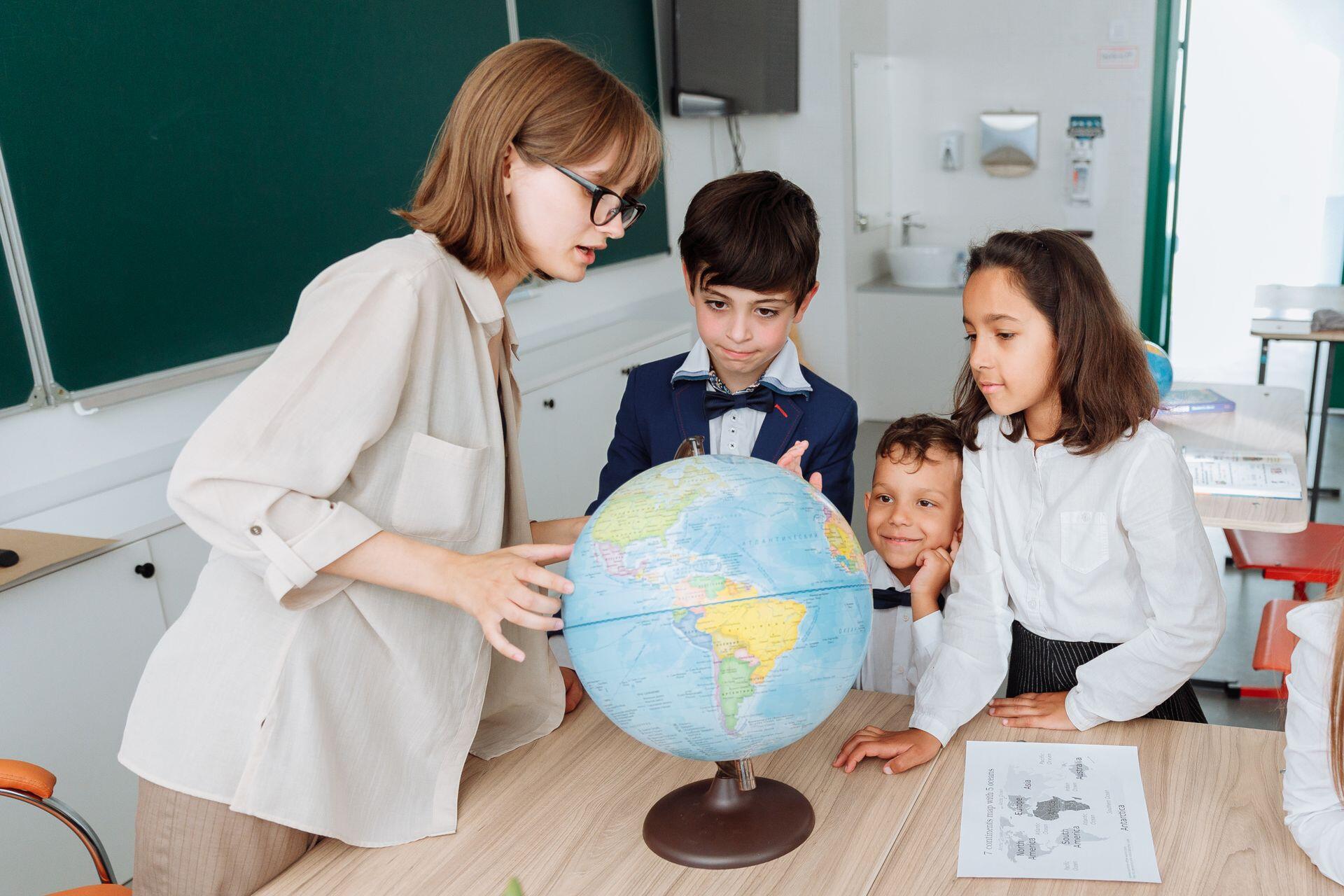 Teacher and students gather around a globe in a classroom.