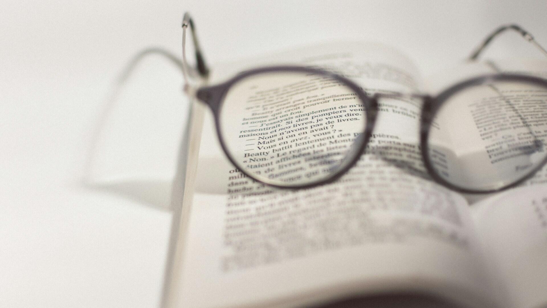 novel open with reading glasses on the page