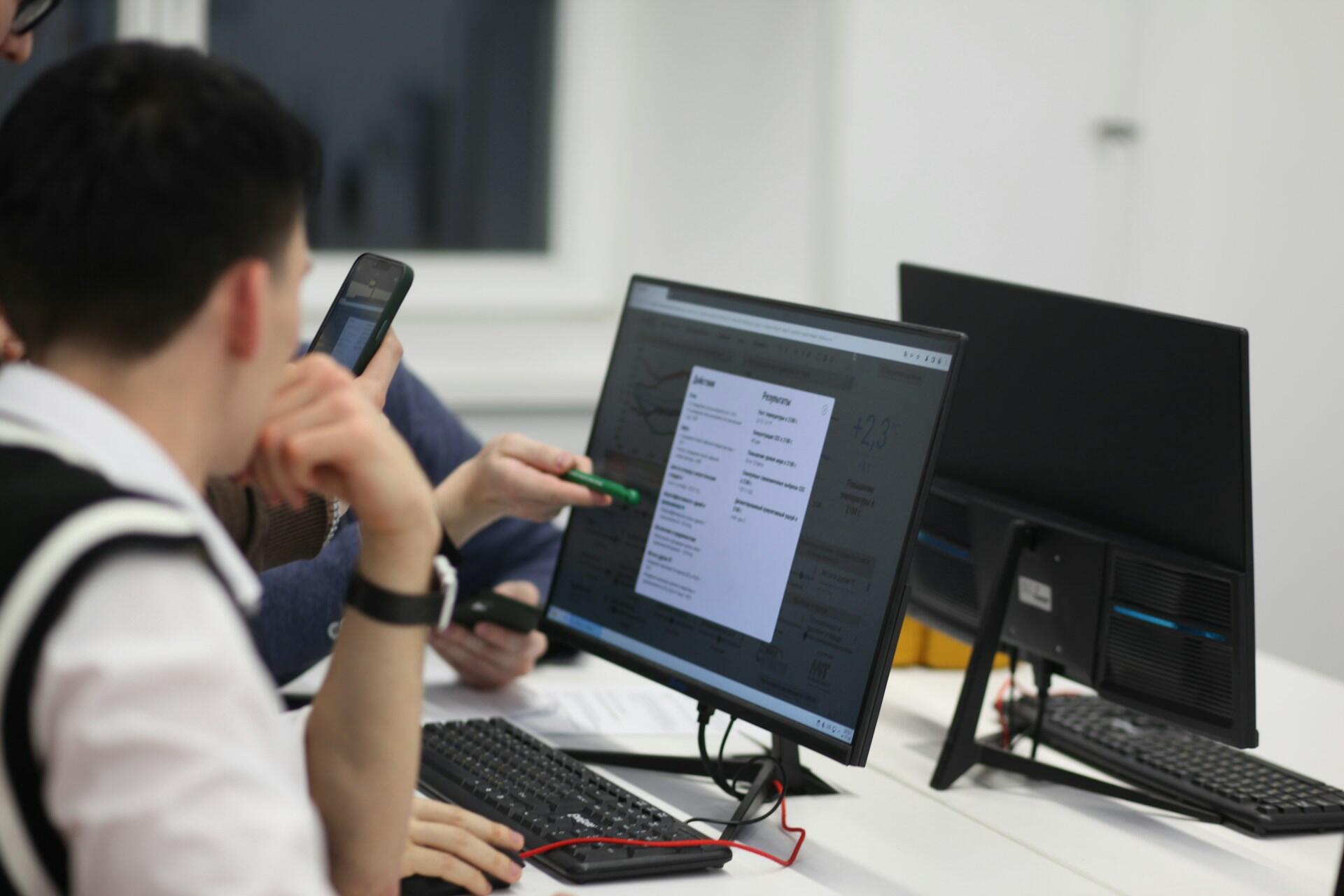 People sitting at a desk and collaborating on computers in a bright office.