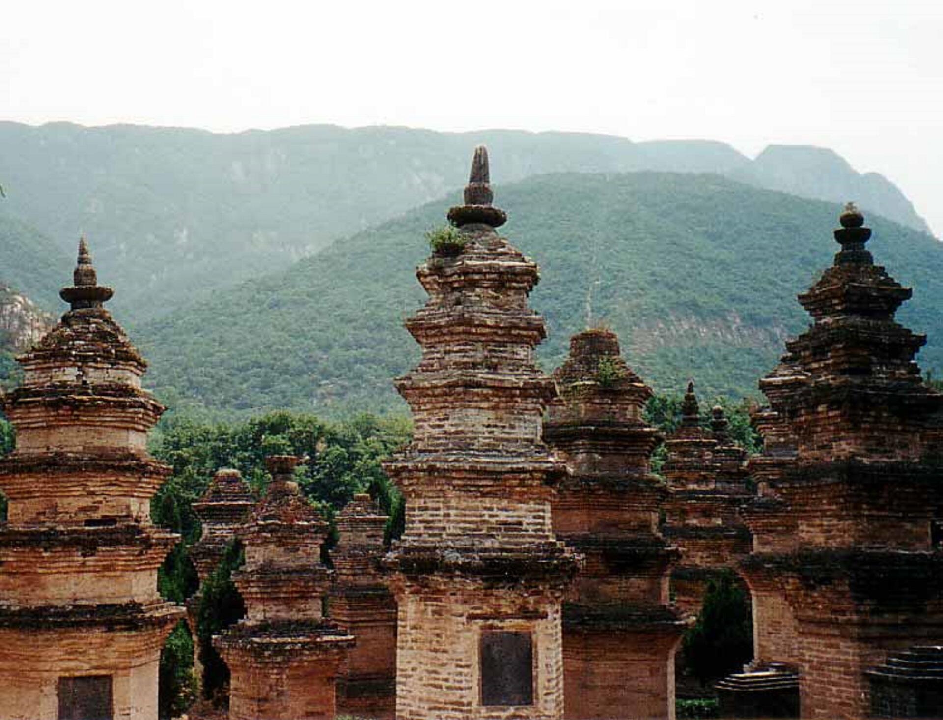 Ancient brick pagodas dot a landscape backed up by forest-covered mountains.