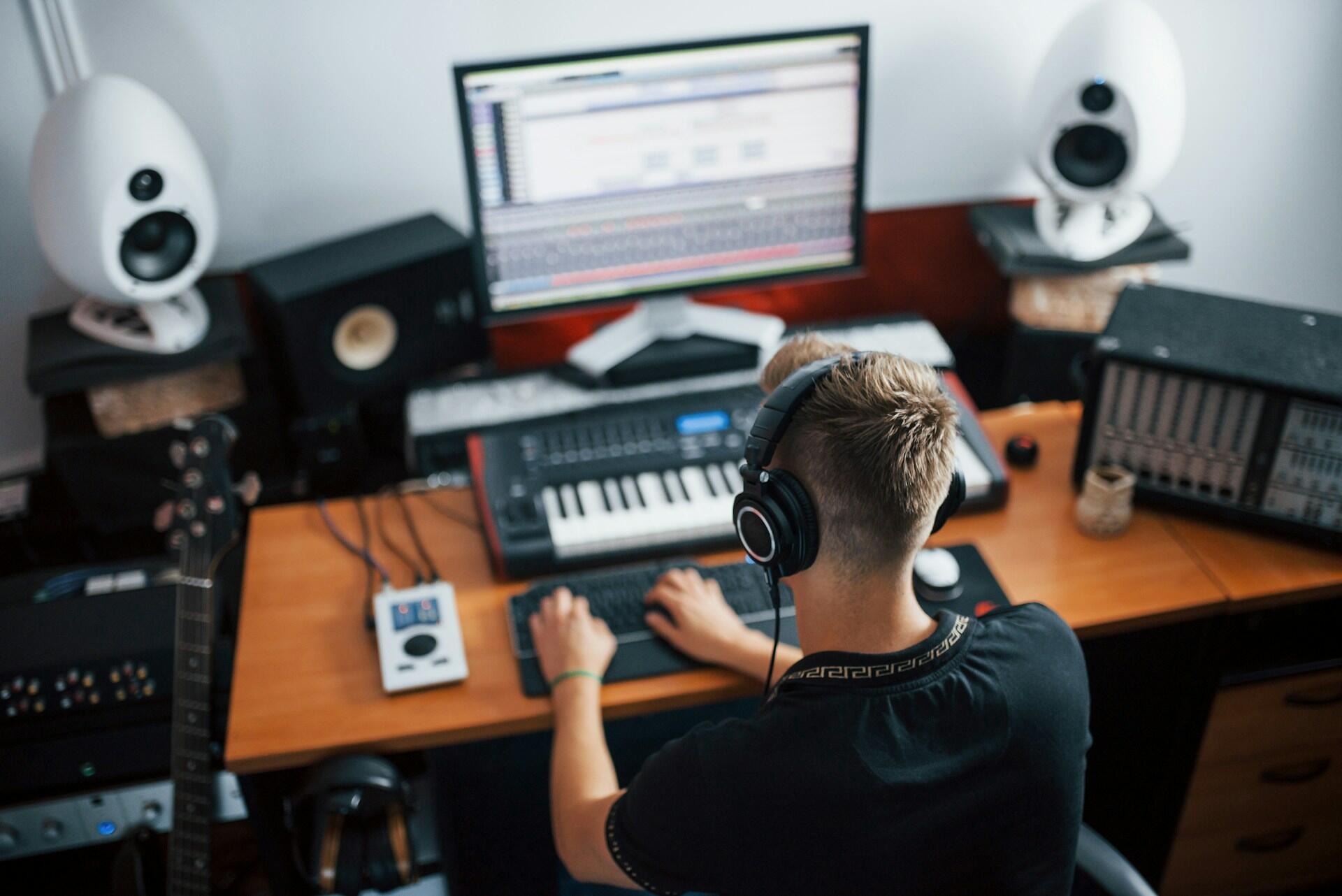 sound designer in a home studio using MIDI and a keyboard to add audio details to a project
