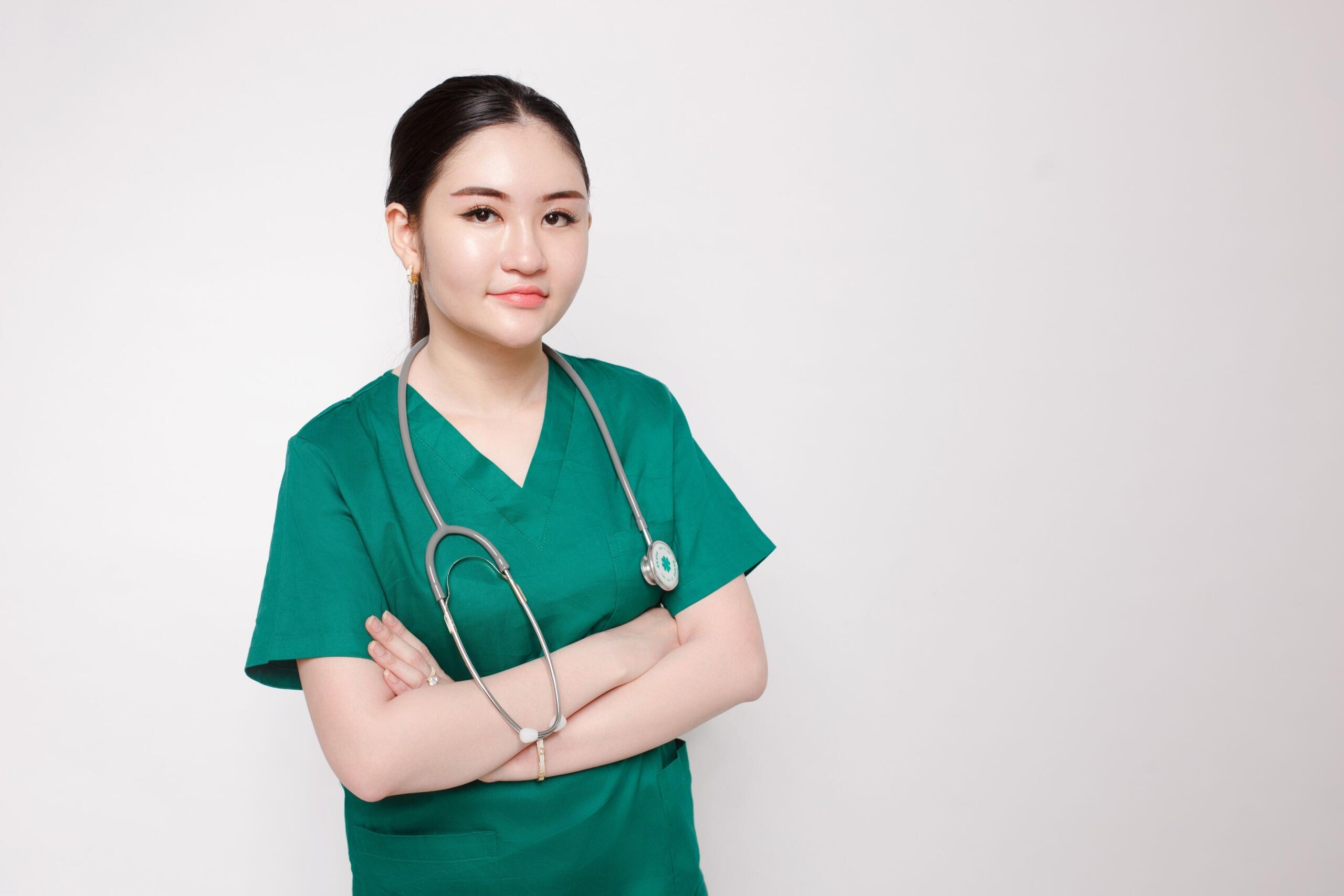Female doctor or nurse in green scrubs with a stethoscope around neck