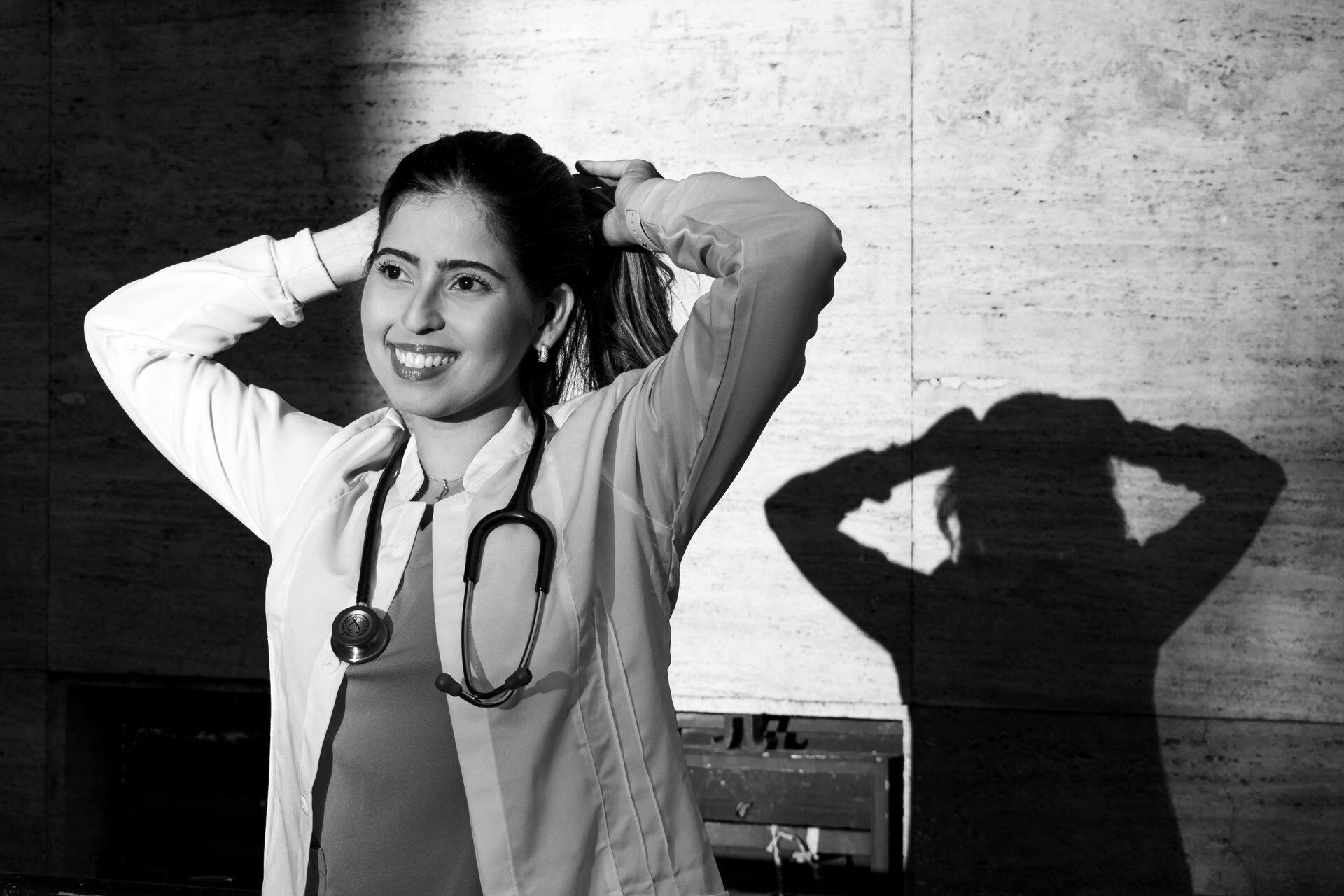 Black and white image of lady in medical attire tying up her hair