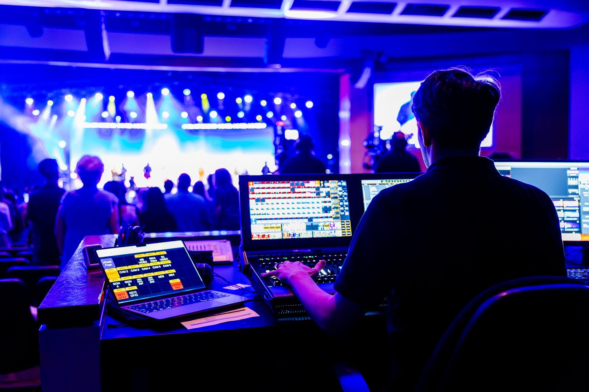 event producer audio or visual technician with many screens, each displaying a different element of the live concert being performed in front of them
