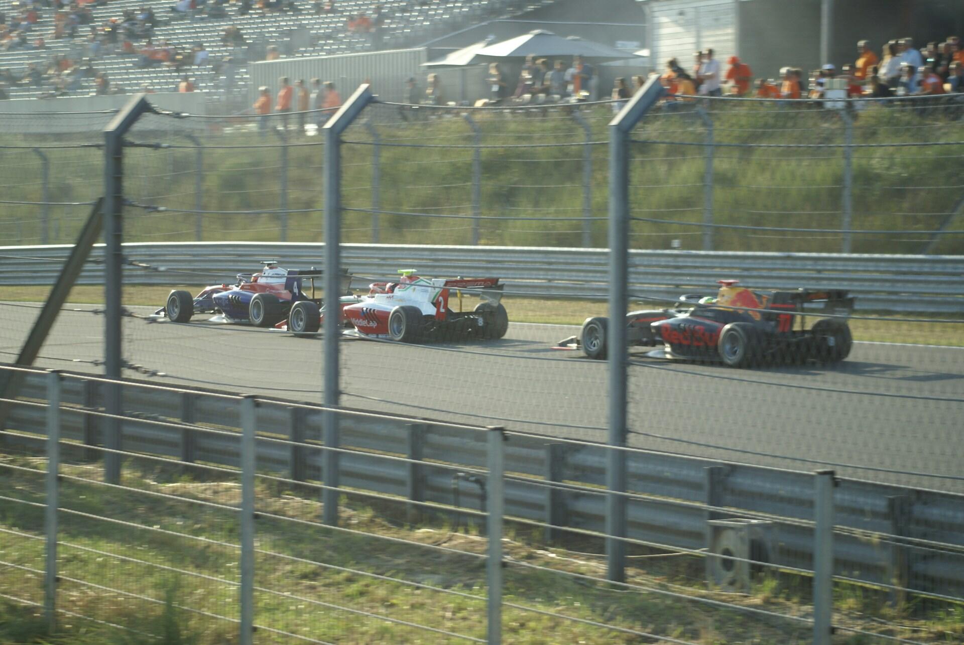 A group of colorful racing cars speeds around a track during a competitive race.