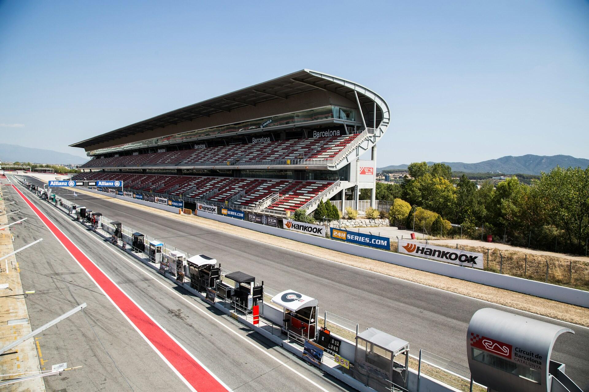 An empty racetrack surrounded by numerous parked cars, showcasing a quiet and desolate scene.