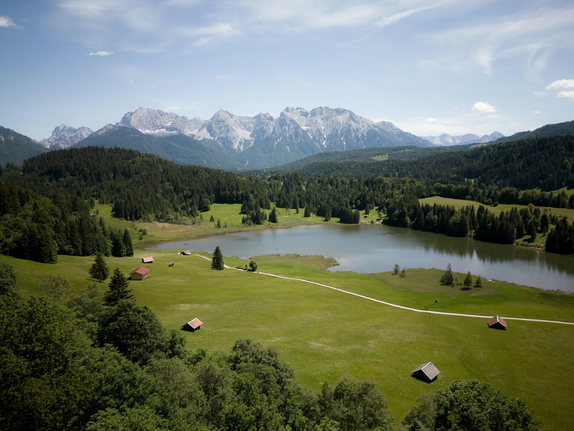 Scenic landscape of a lake surrounded by green meadows in Krün, Germany.