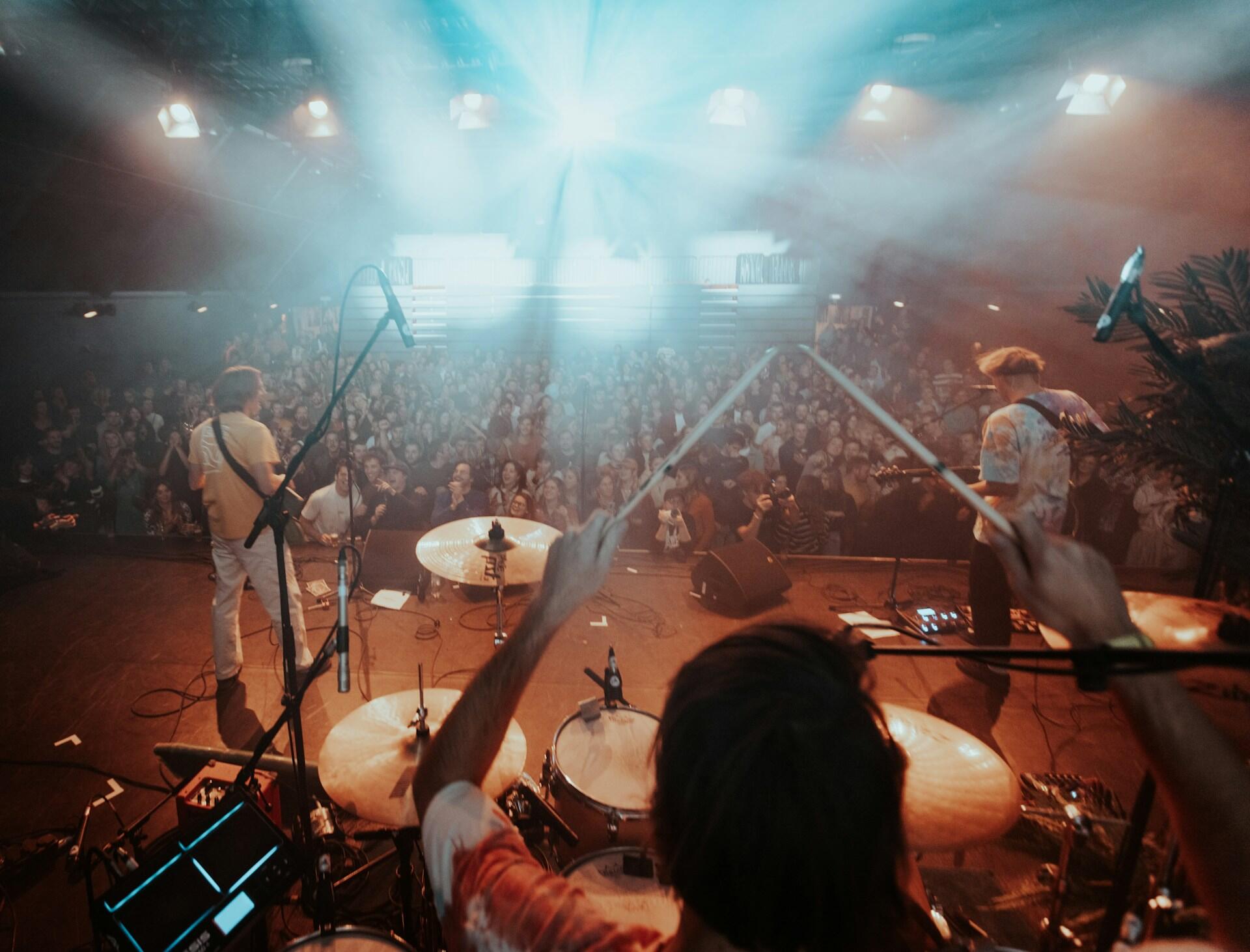 a band on stage playing to a large crowd in a venue