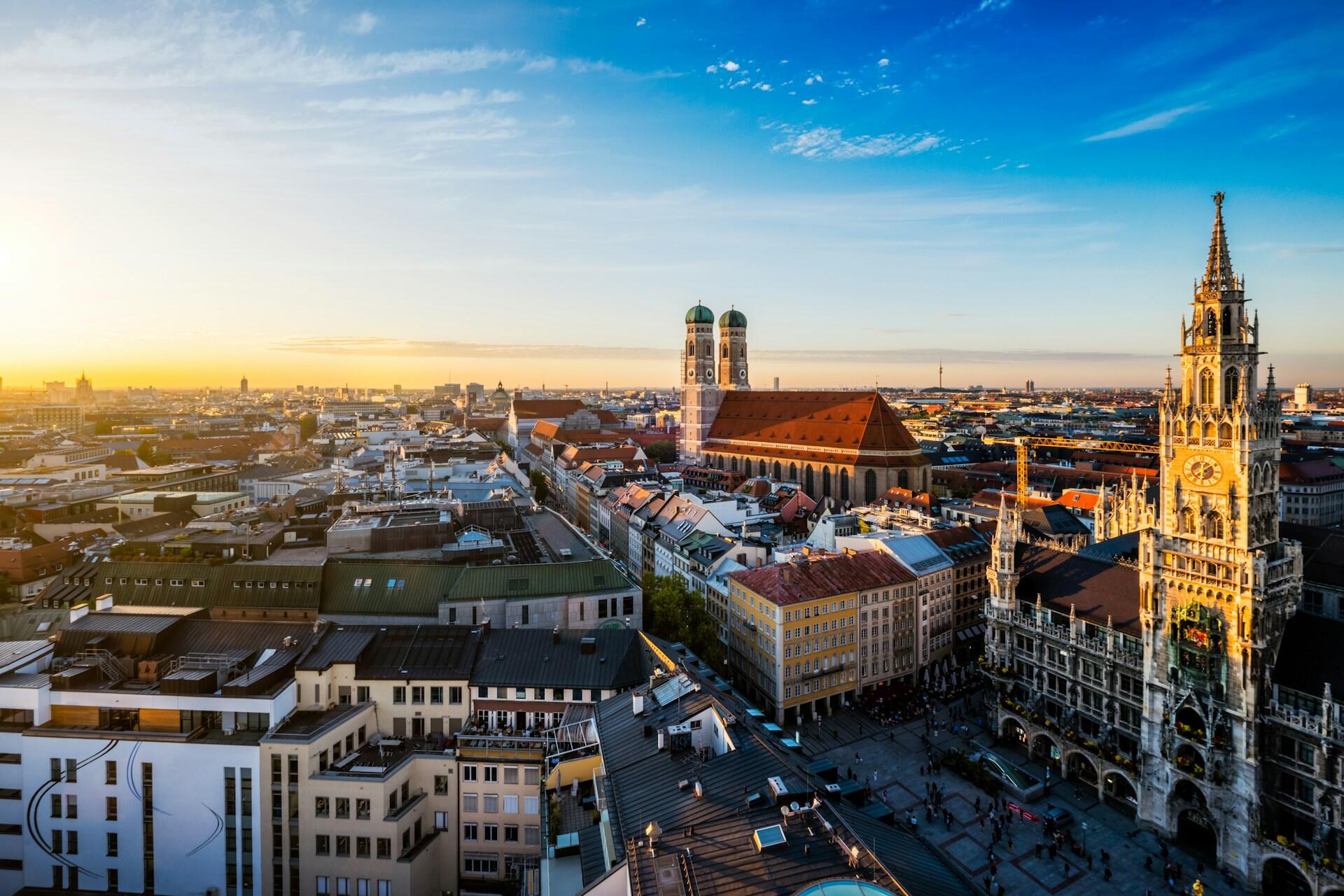 Aerial view of Munich city at sunset, featuring Frauenkirche with twin domes.