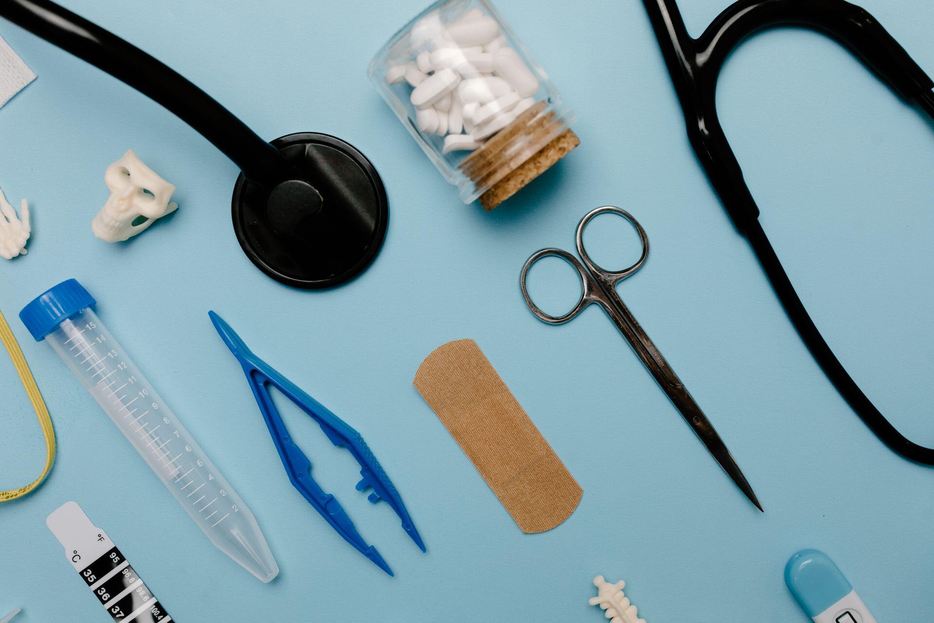 a variety of medical tools on a table including scissors, a plaster, tablets, and more