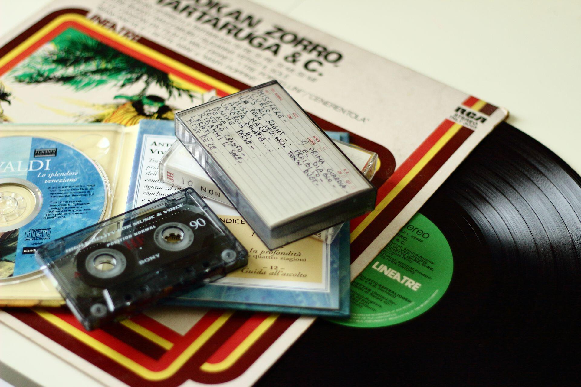 a pile of vinyl discs with CDs and cassette tapes resting on top