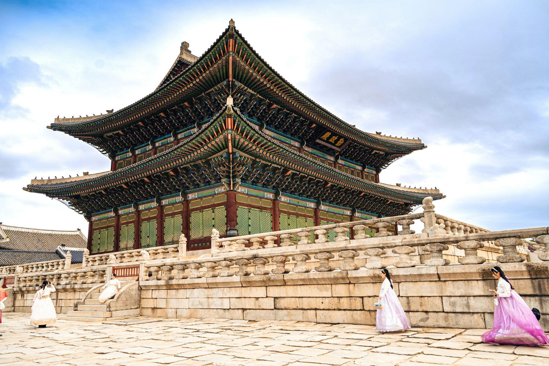 Traditional Korean palace building with visitors wearing hanbok