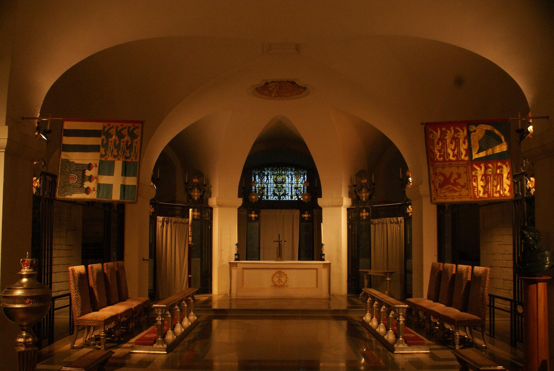 Interior view of a chapel showcasing a prominent altar and neatly arranged benches for worshippers.
