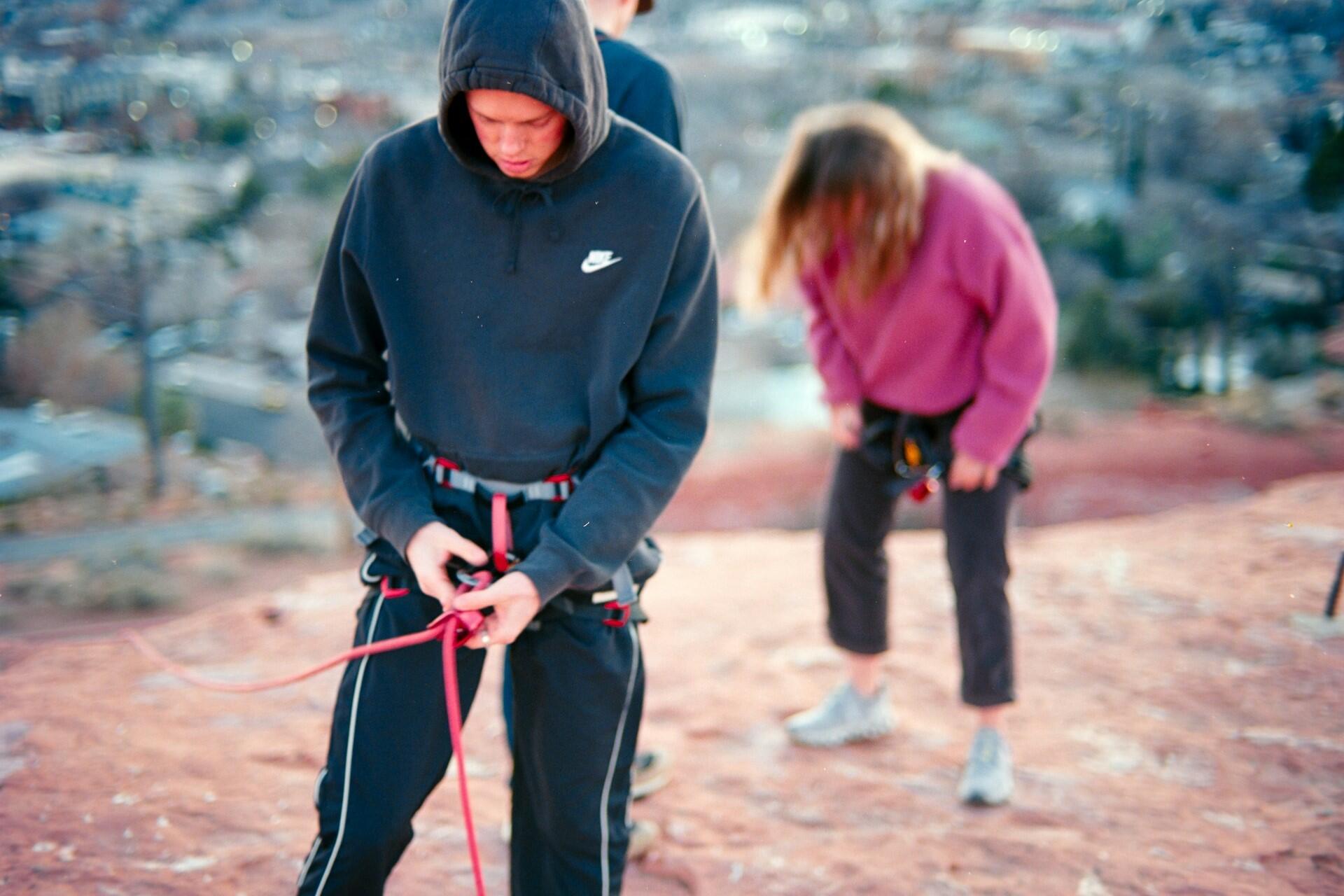 Two climbers wearing harnesses preparing a rope before outdoor climbing