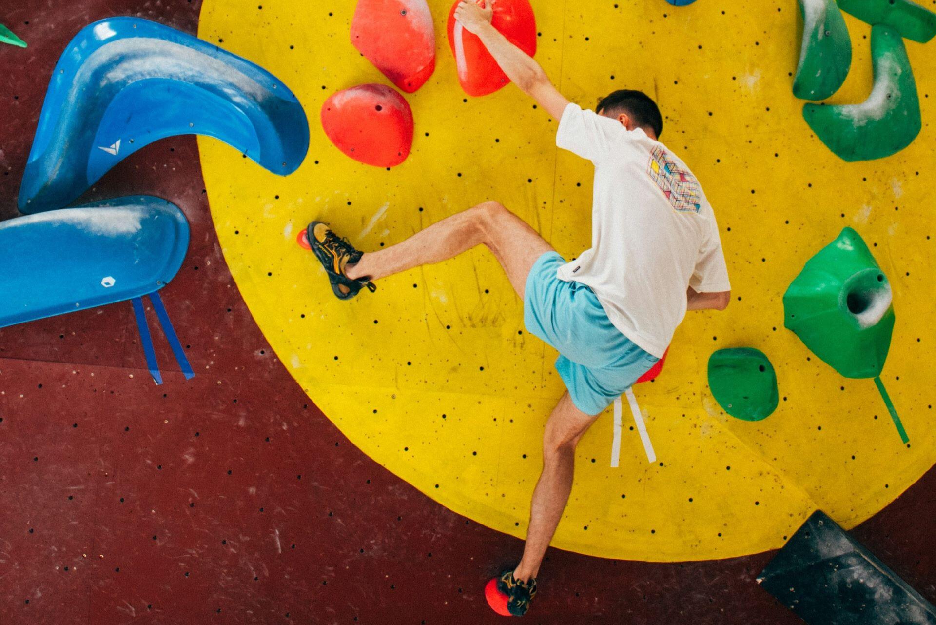 Climber scaling a colourful indoor bouldering wall