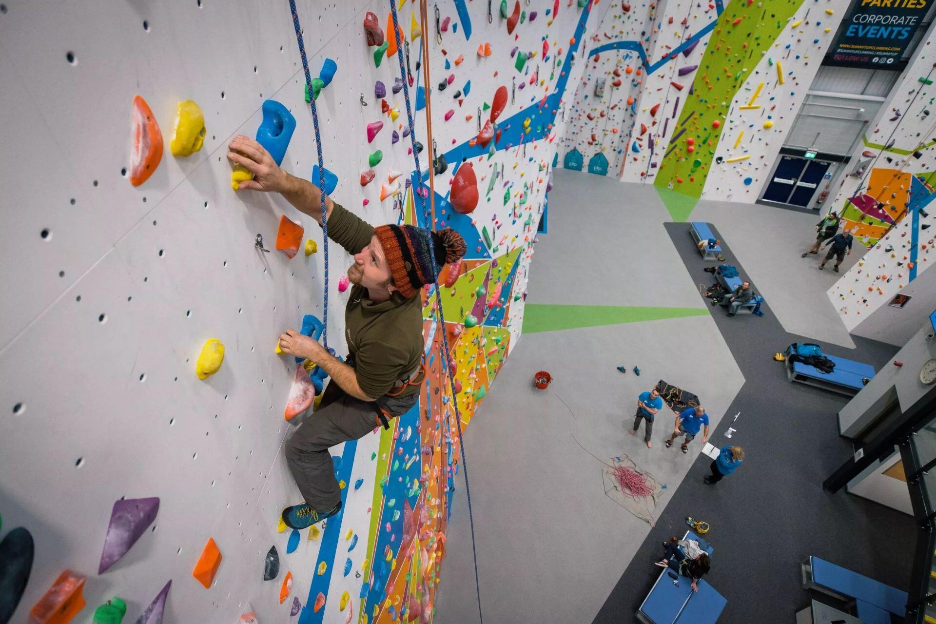 Climber ascending a colourful roped wall at Summit Up Oldham