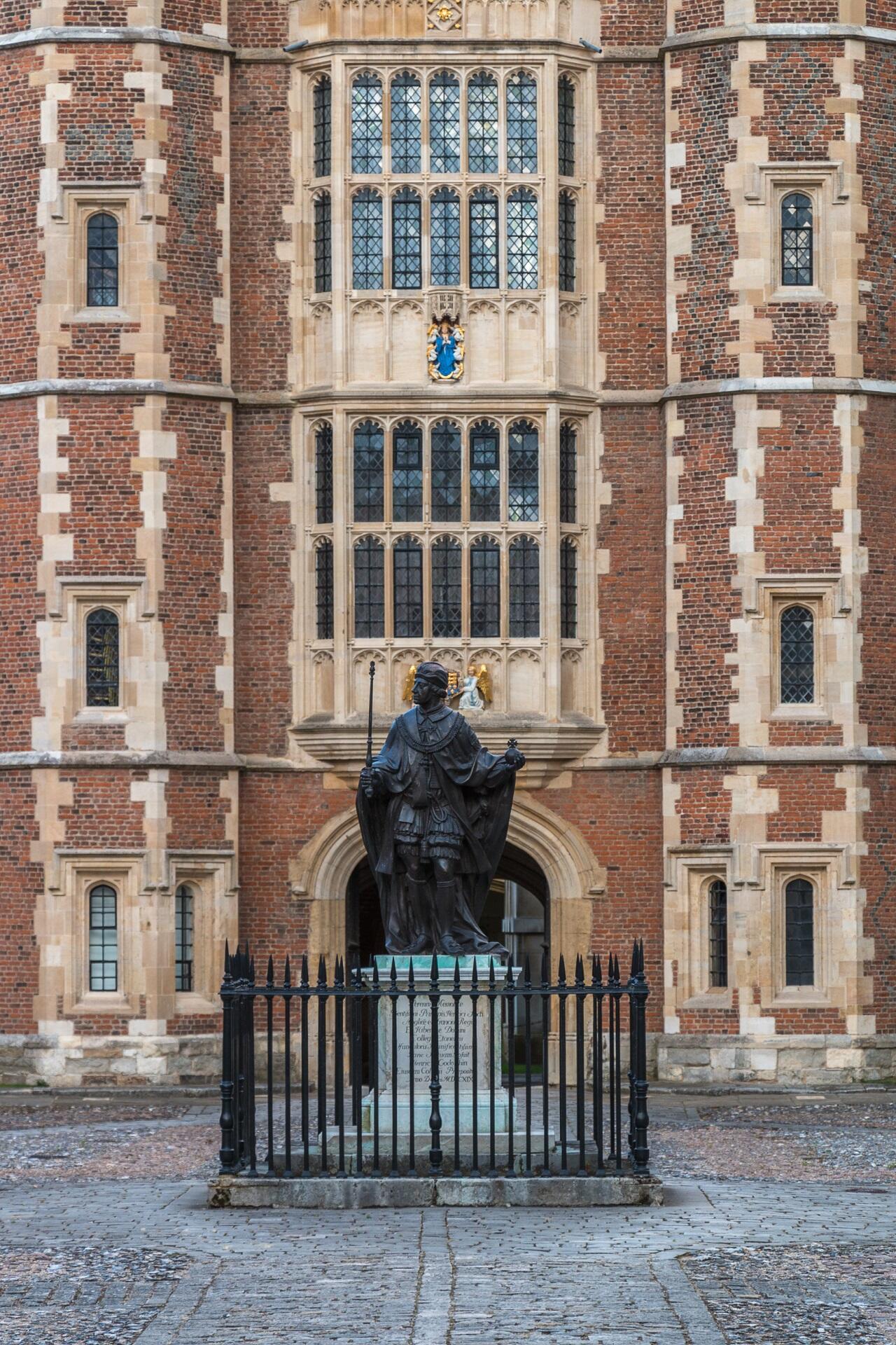 A detailed statue of King Henry VI is displayed in front of an impressive building, blending art with architecture.