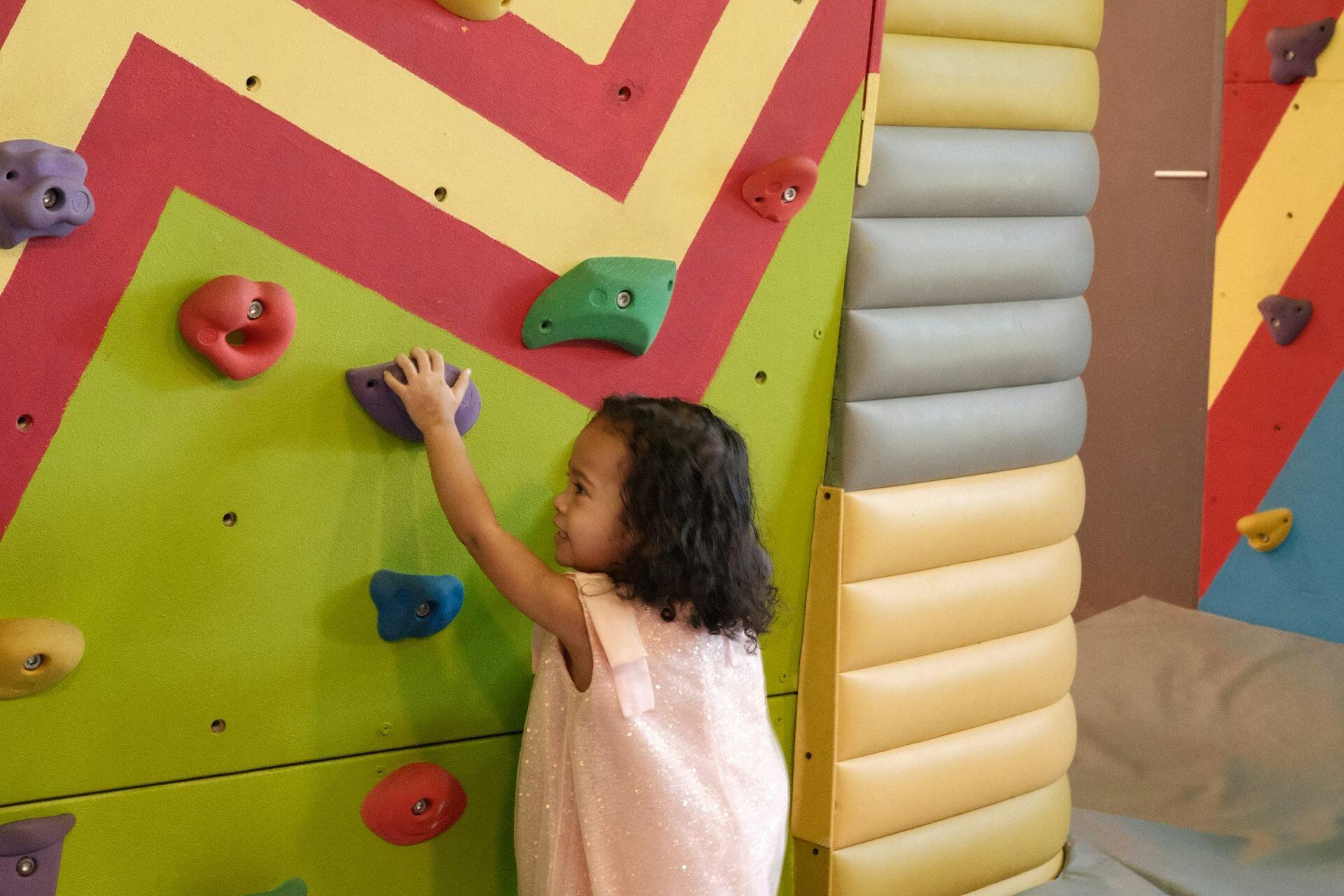 Young child climbing a colourful indoor climbing wall