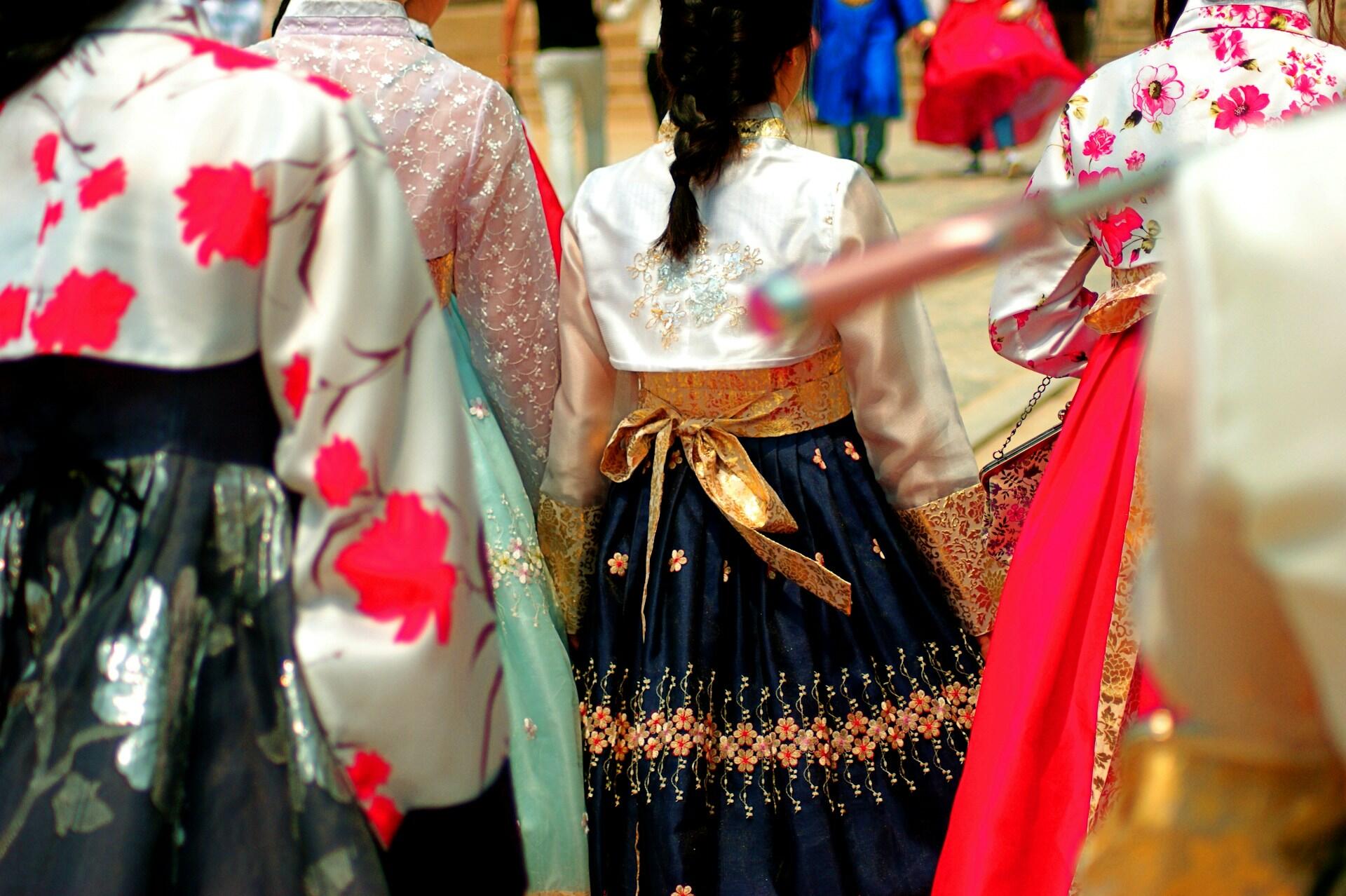 Many people wearing hanbok of various colours, all standing close together outdoors.