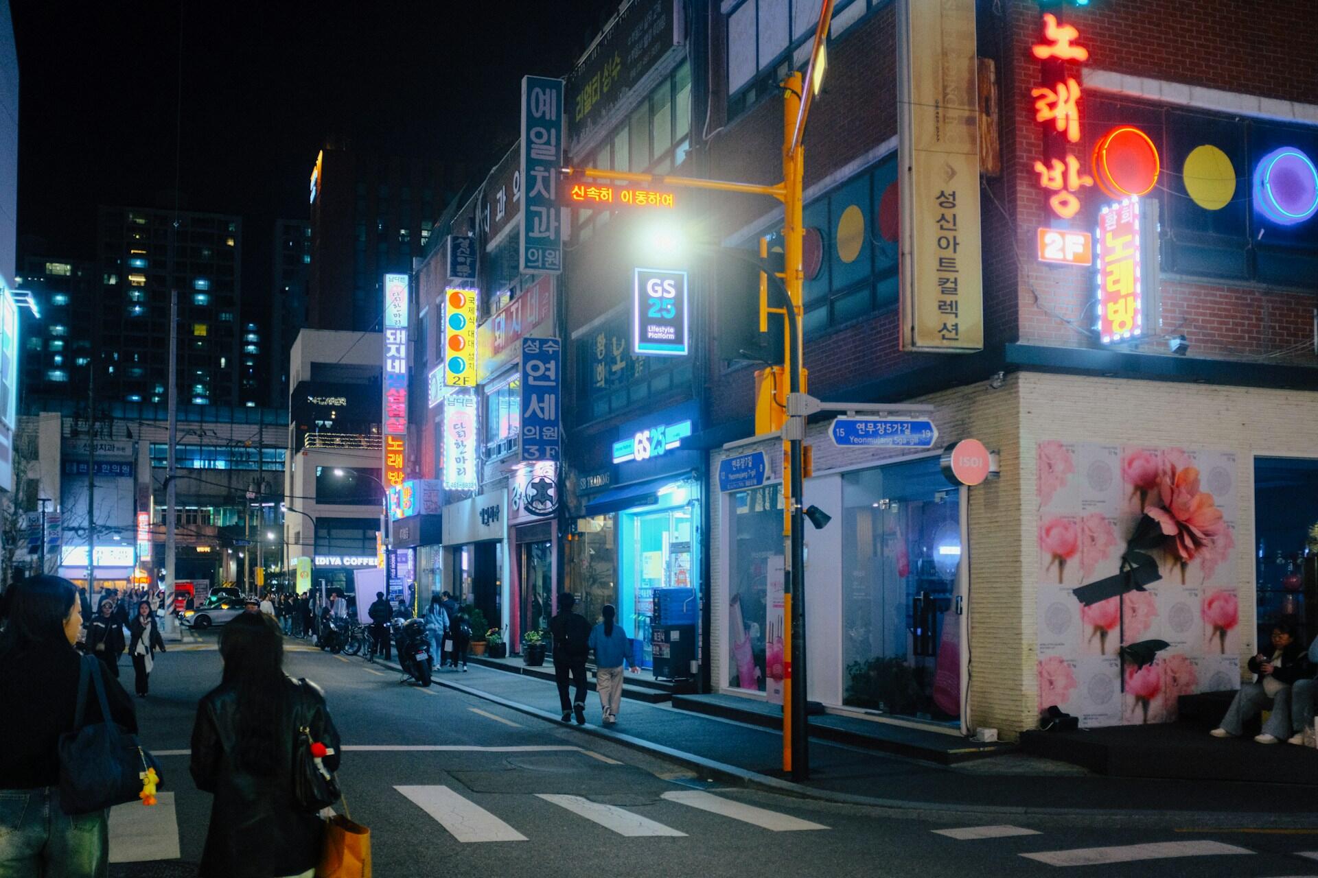 Neon-lit Seoul street lined with shops and pedestrians at night