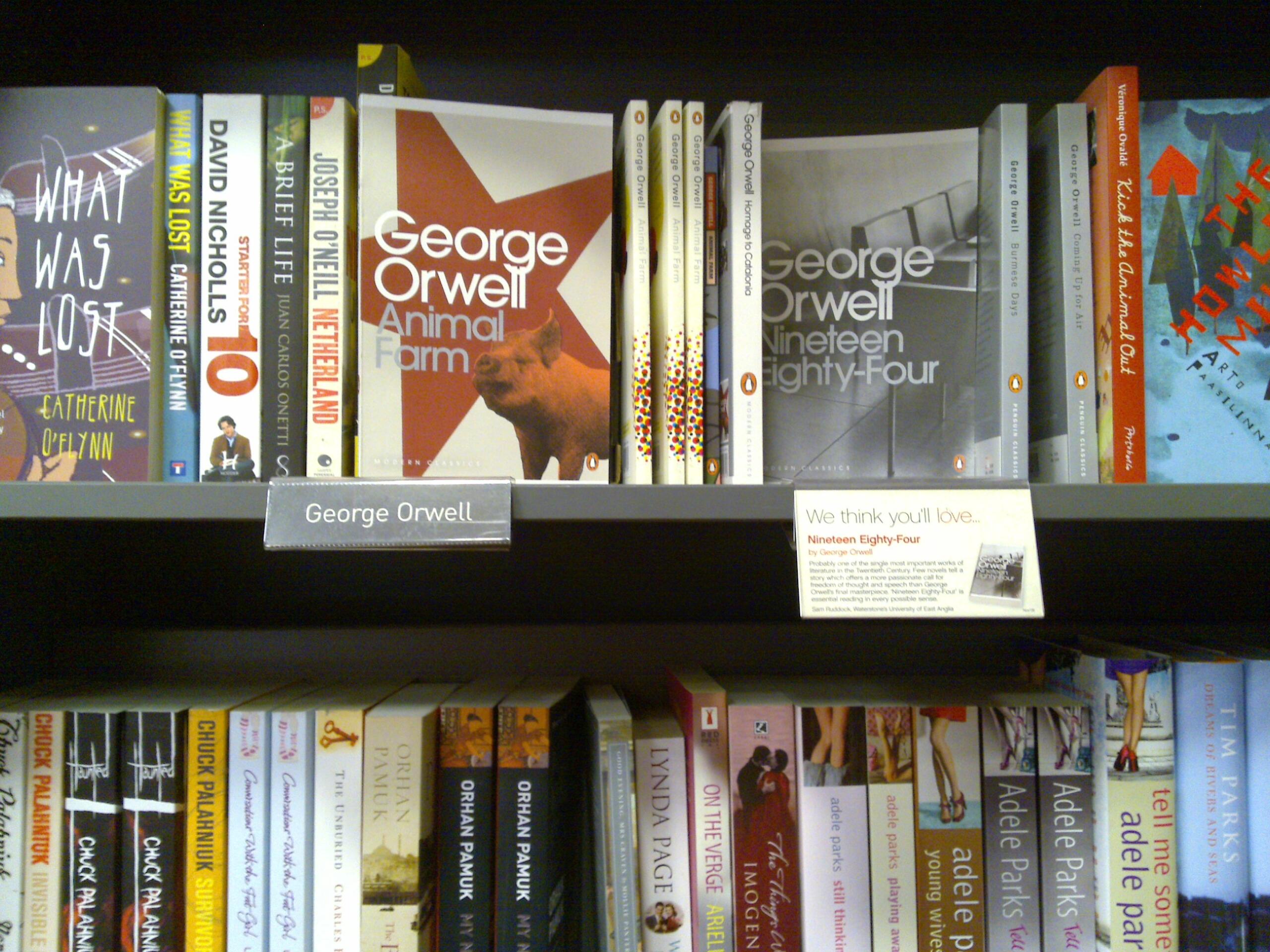 A bookstore shelf displays George Orwell books including Animal Farm and Nineteen Eighty-Four, with a George Orwell label and recommendation sign.