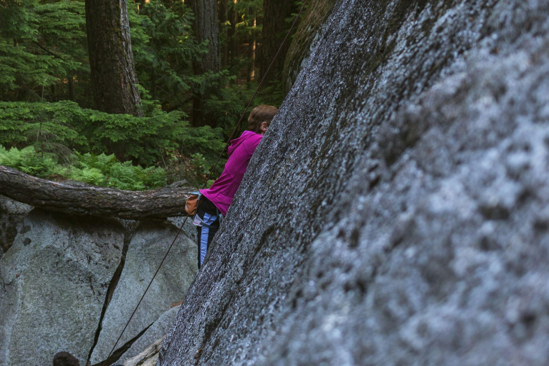 Outdoor climber using a rope on a rock face surrounded by woodland
