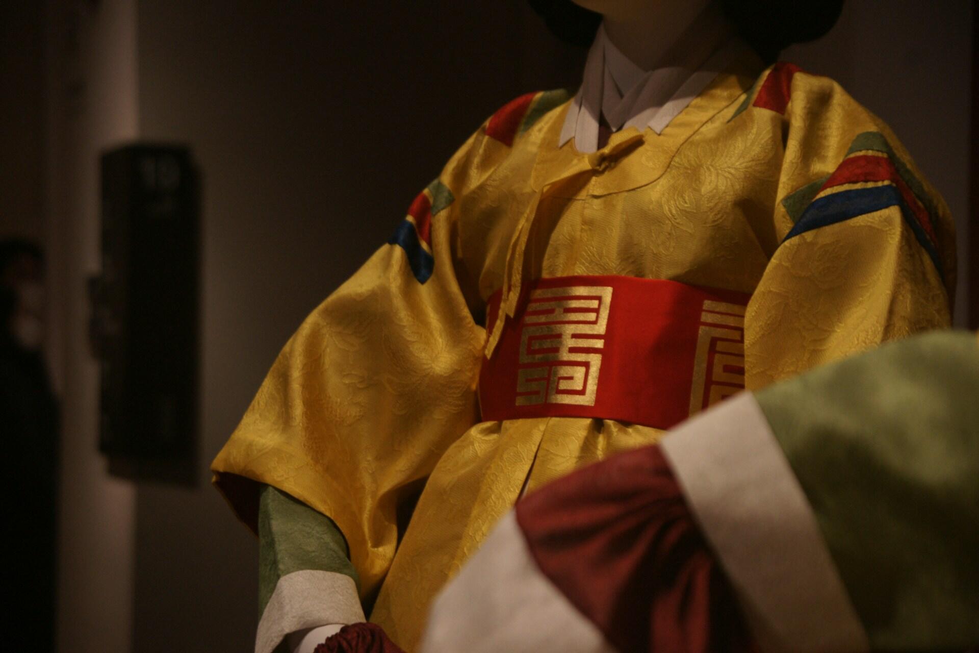 A gold and red garment featuring an intricate pattern woven into the cloth, giving the impression of wealth.