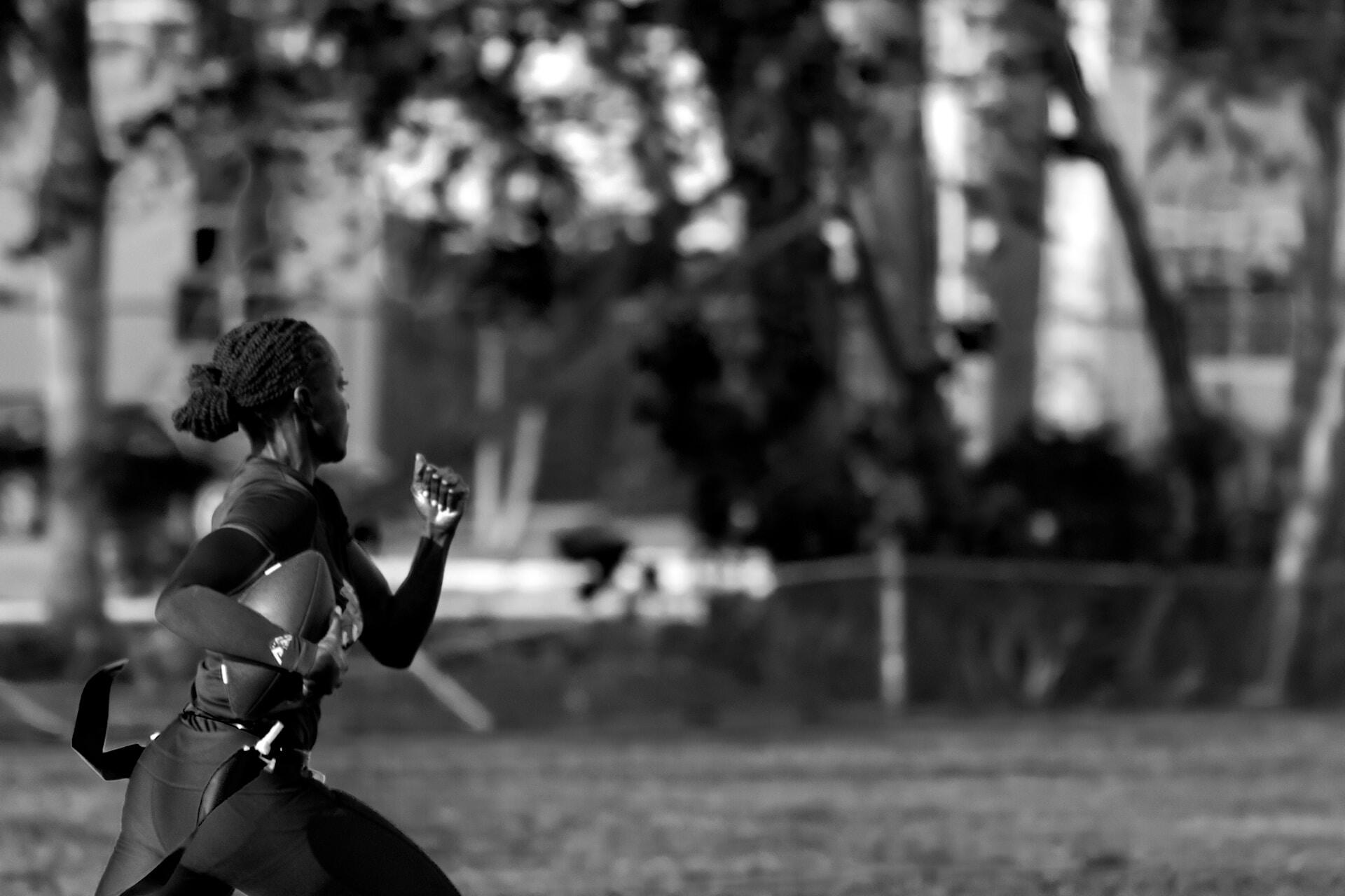 Black and white photo of a female athlete playing flag football.