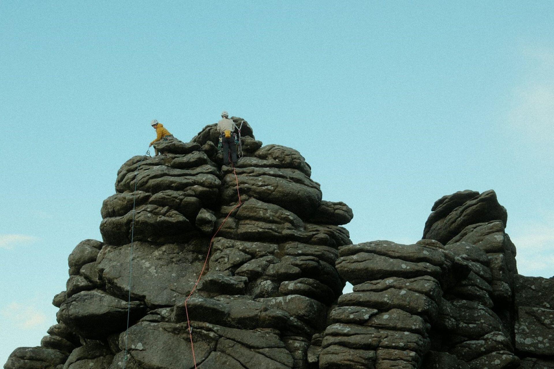 Two climbers on top of a rocky outcrop with climbing ropes