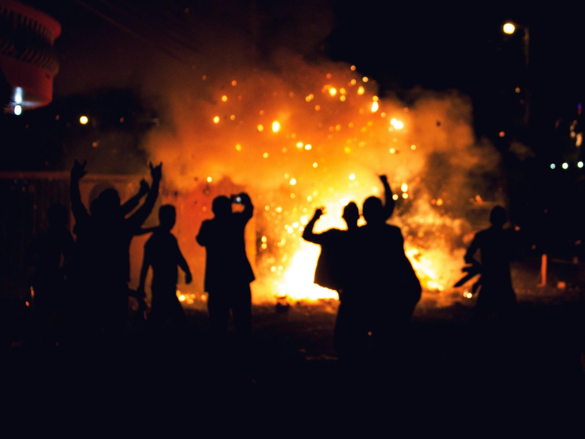 People celebrating in front of a large bonfire. The mood is festive and joyous.