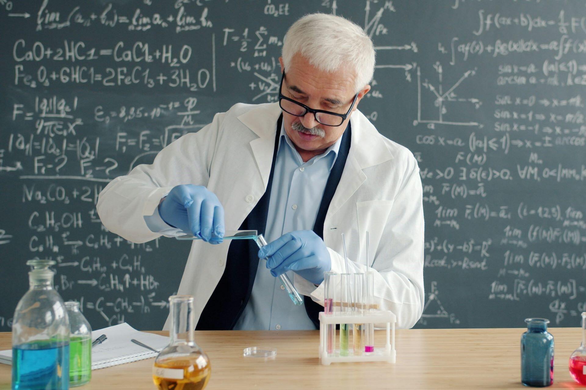 Scientist in a lab coat holding test tubes at a laboratory bench
