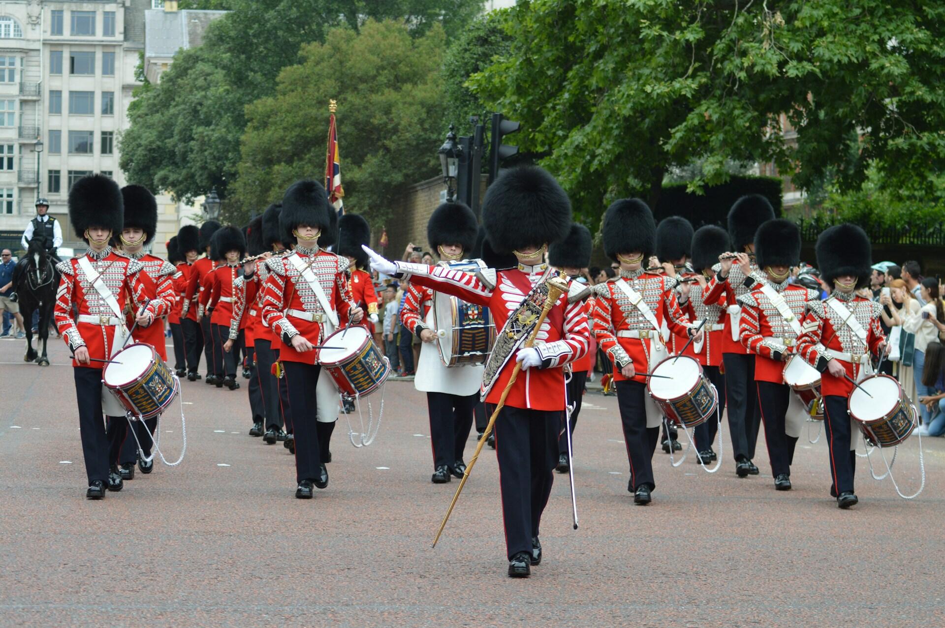 British military marching band in full regalia led by a drum major in the front