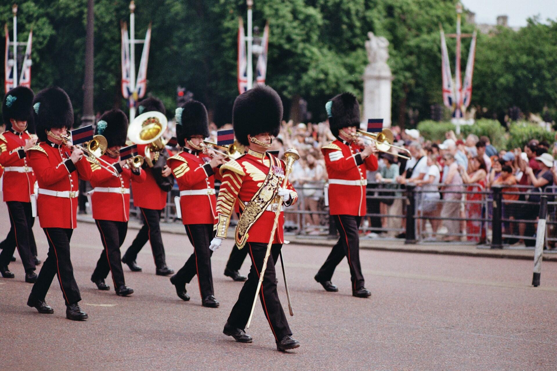 British military band marching in formation with the drum major at the front with a large baton