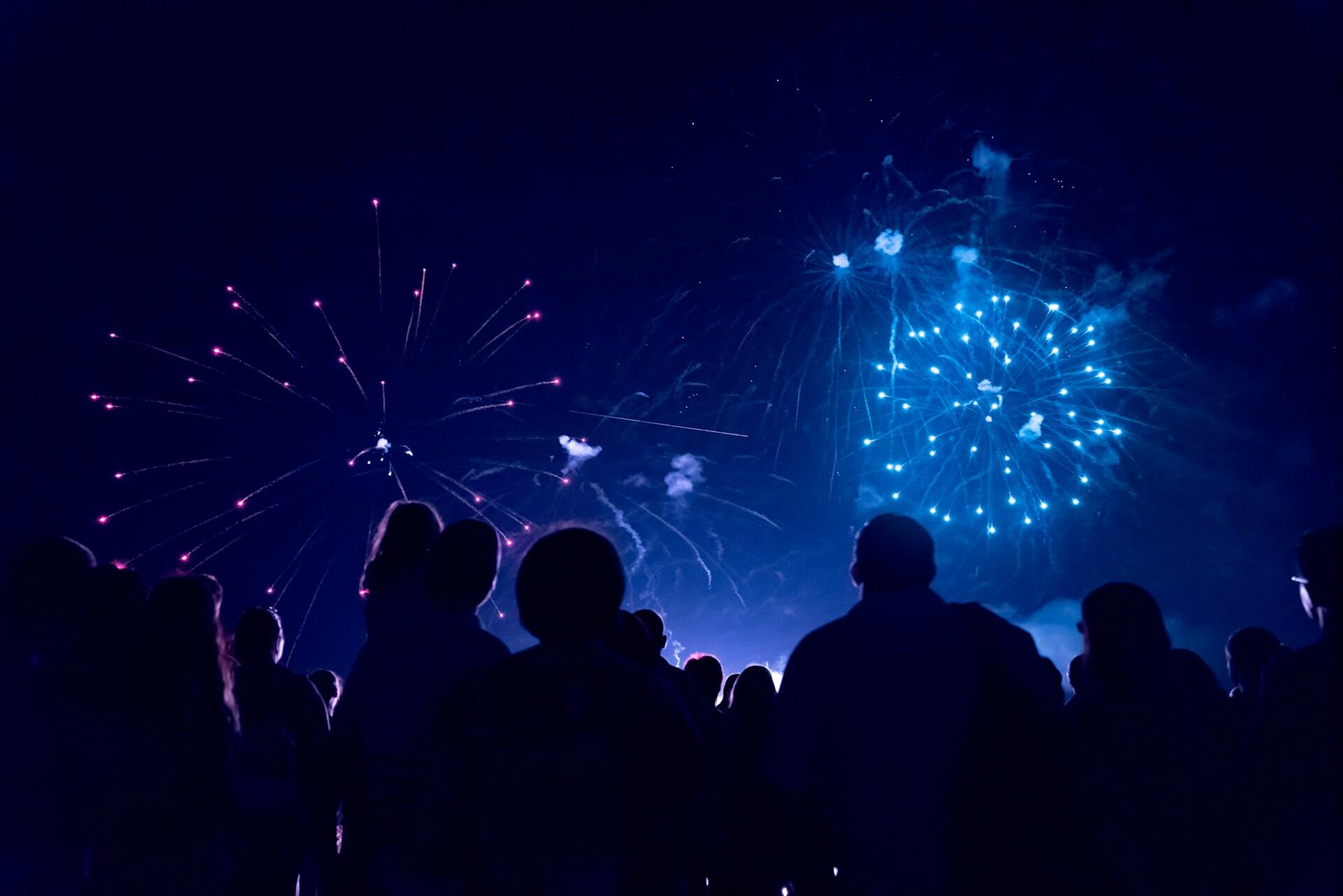People enjoying a fireworks display at night. The mood is festive and celebratory.
