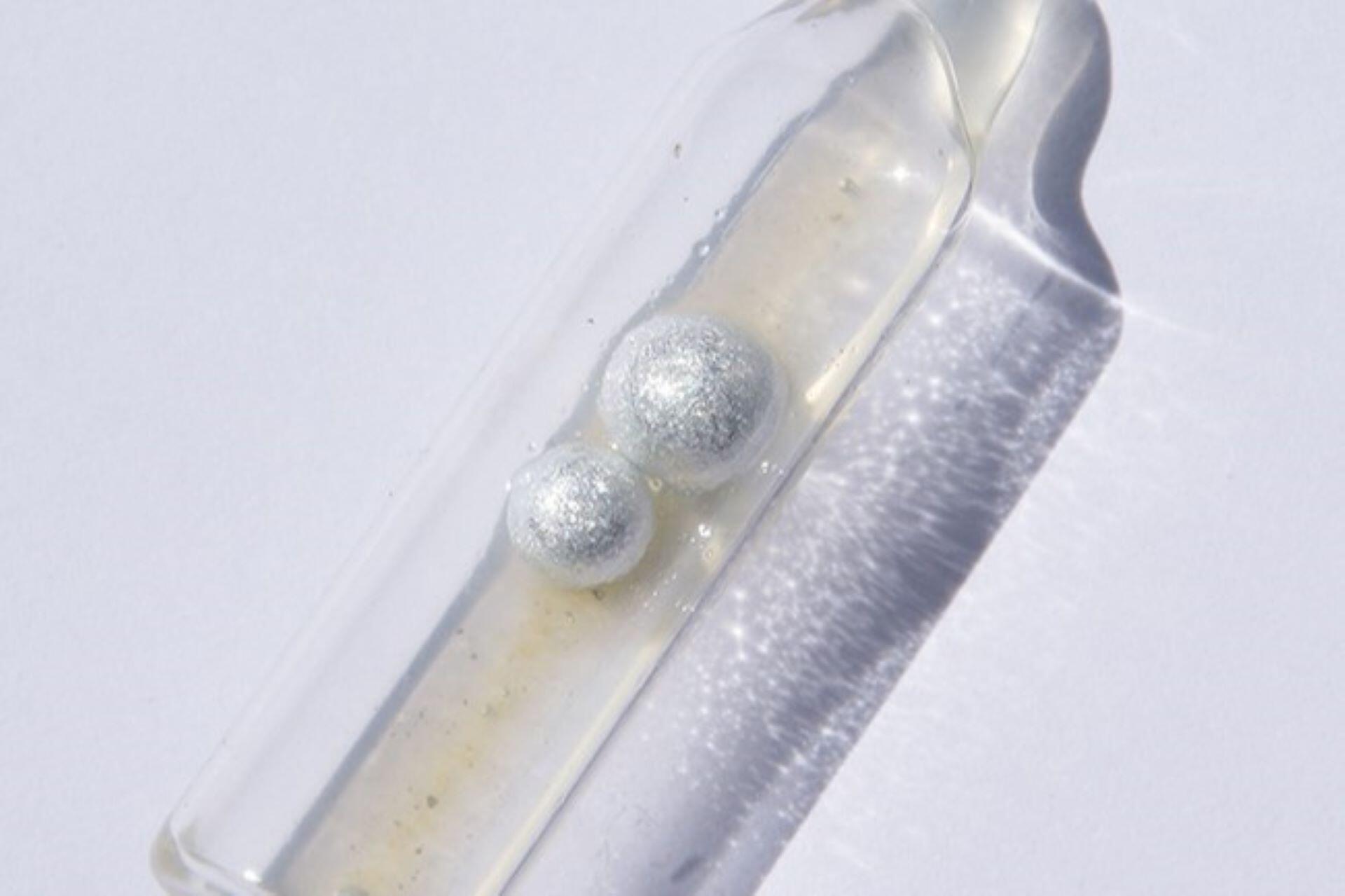 Silvery alkali metal samples stored under liquid inside a sealed glass tube.