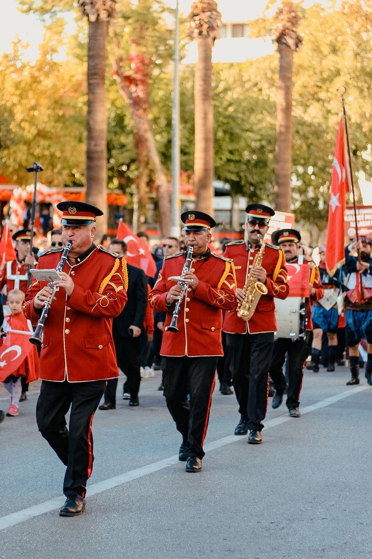 marching band players wearing red regalia uniforms and playing clarinets while marching