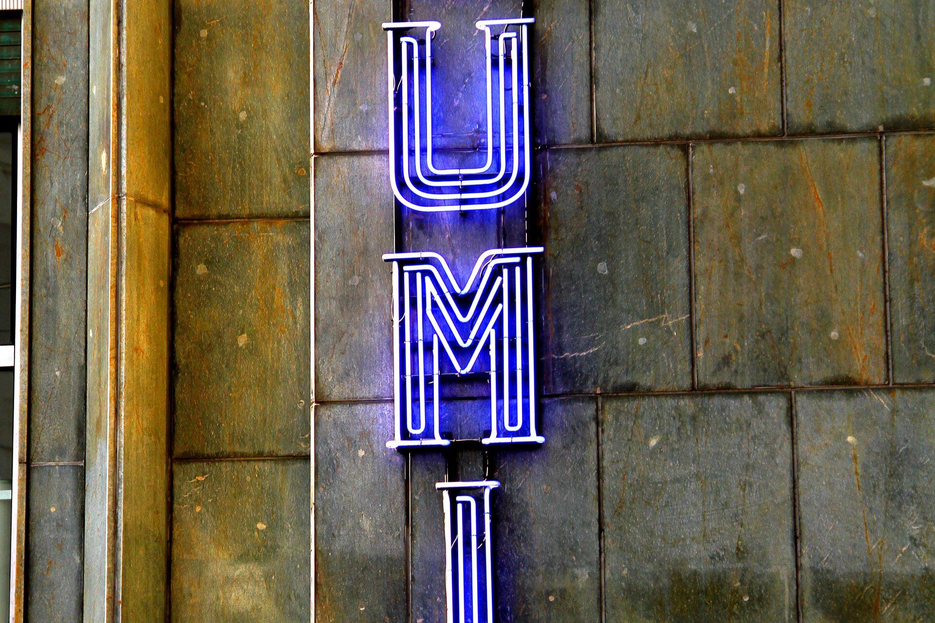 Blue neon sign on a stone wall