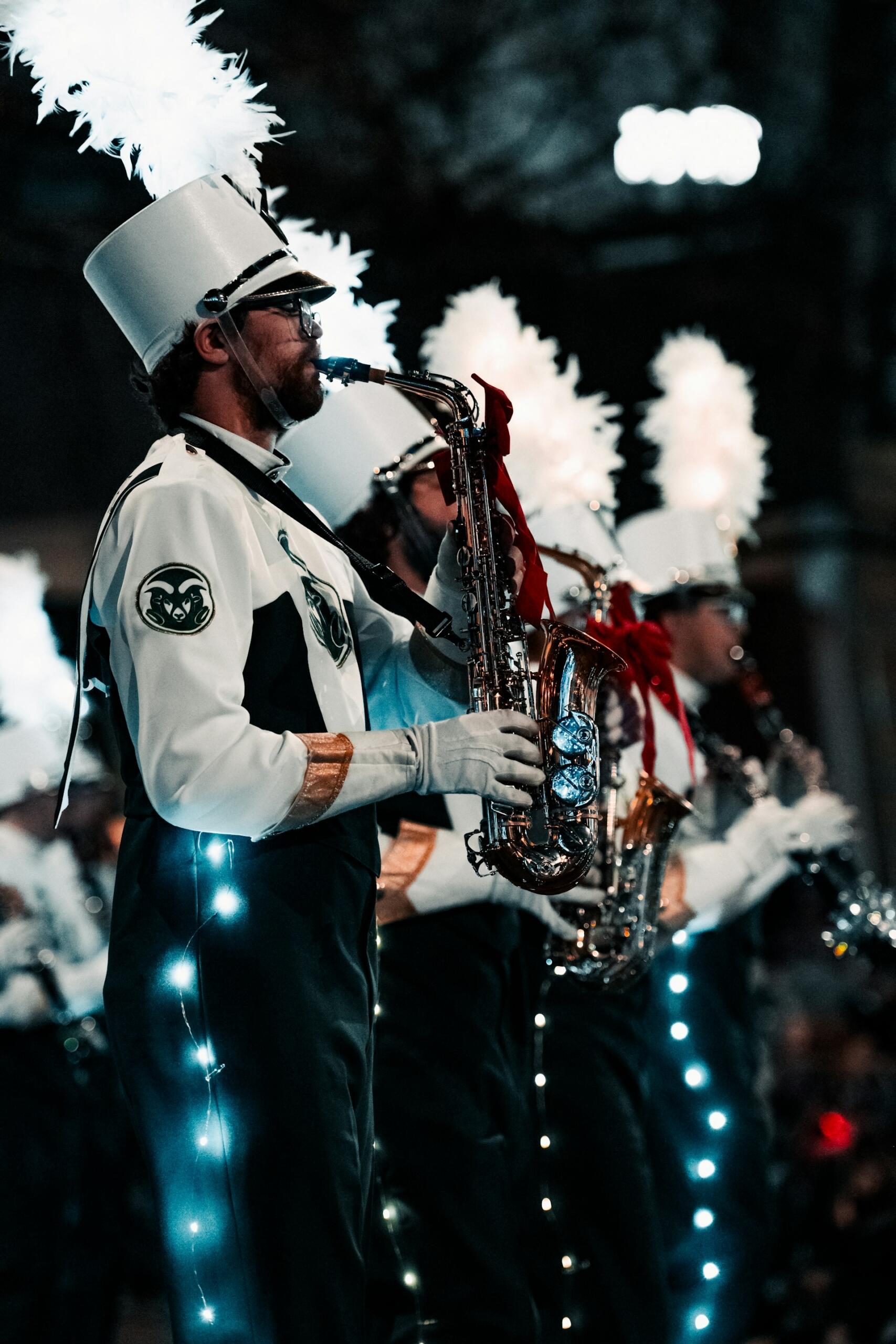 Saxophone players in a marching band, wearing their regalia while standing up playing sax