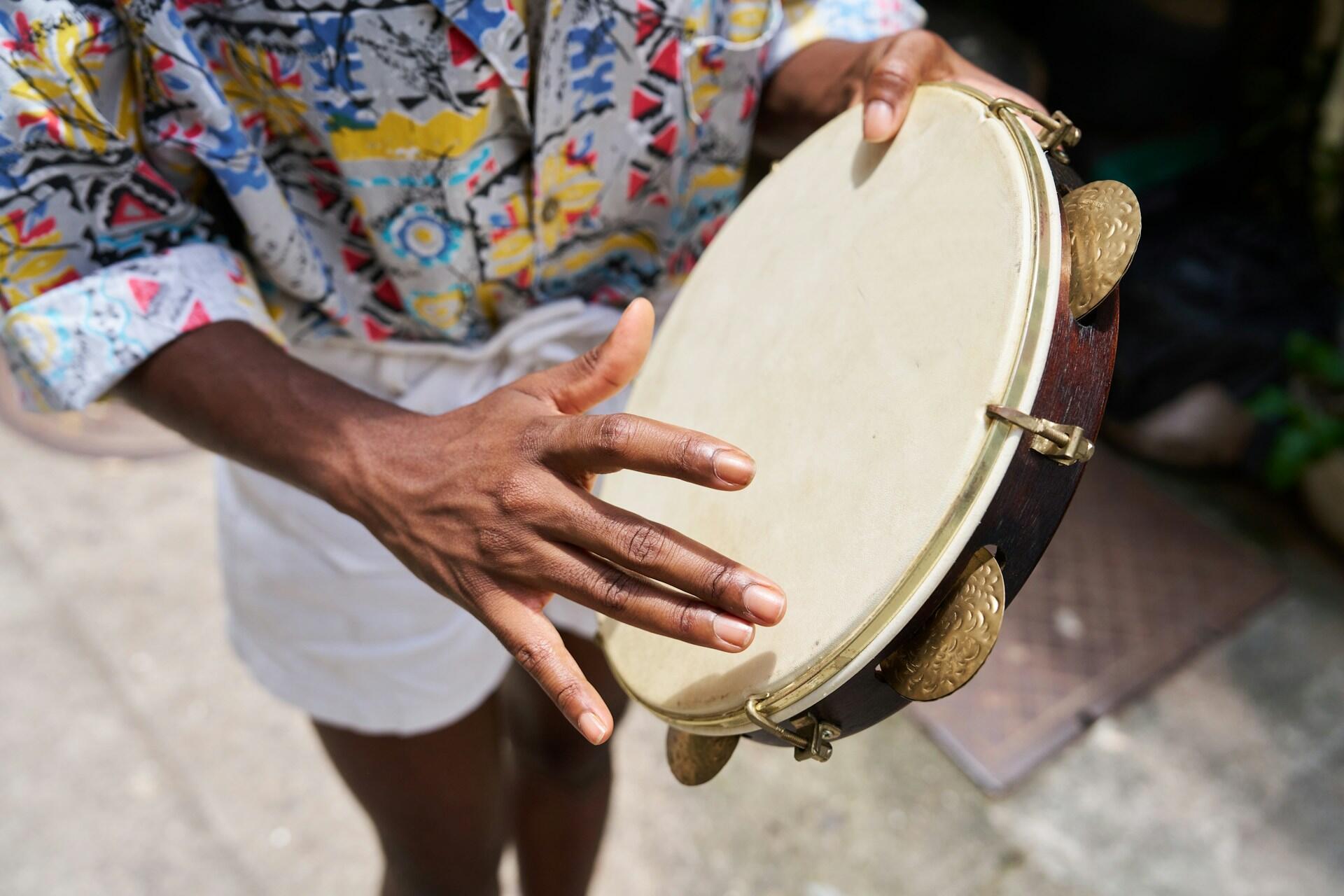 Pandeiro player demonstrating how to play the pandeiro, which looks like a tambourine with a drumhead but has fewer jingles