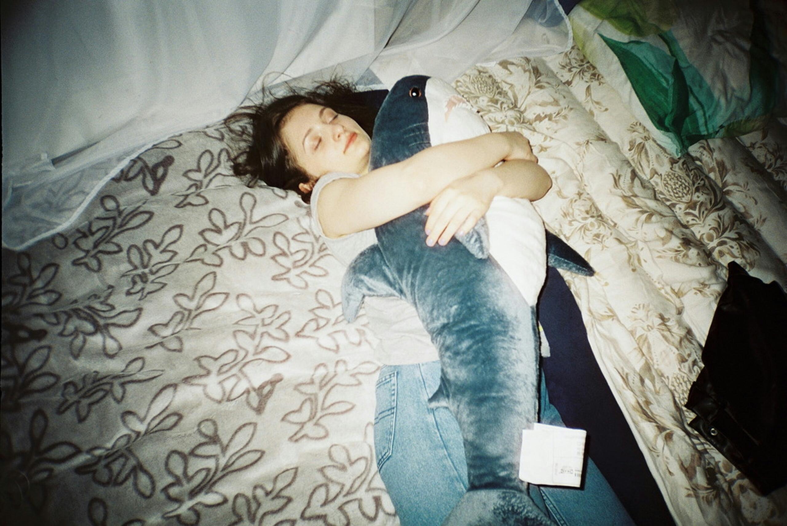 Κορίτσι κοιμάται αγκαλιά με λούτρινο παιχνίδι πάνω σε κρεβάτι, δείχνοντας ξεκούραση μετά από μια γεμάτη ημέρα.