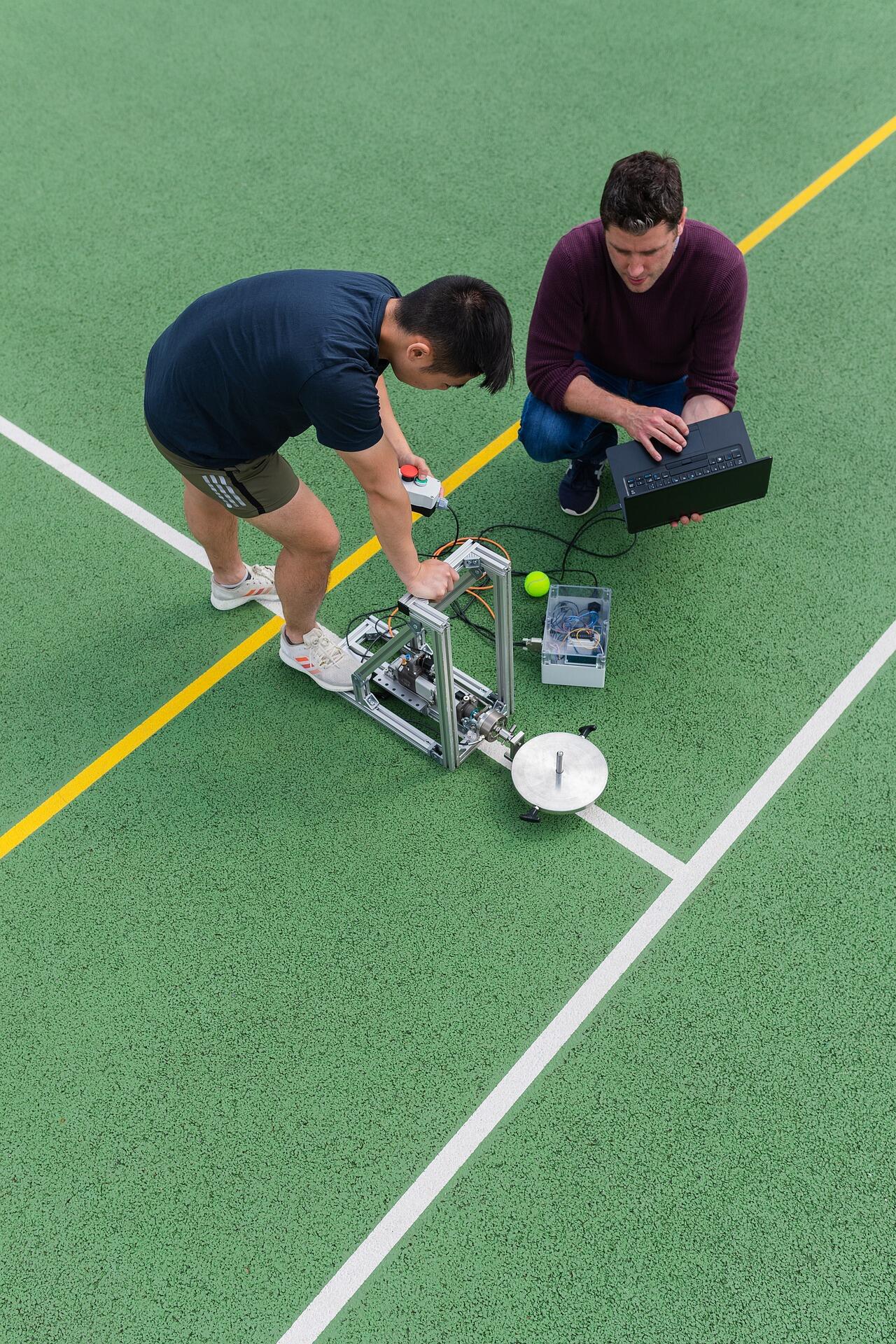 Φοιτητής και καθηγητής χρησιμοποιούν όργανα και υπολογιστή για μετρήσεις σε χώρο στίβου.