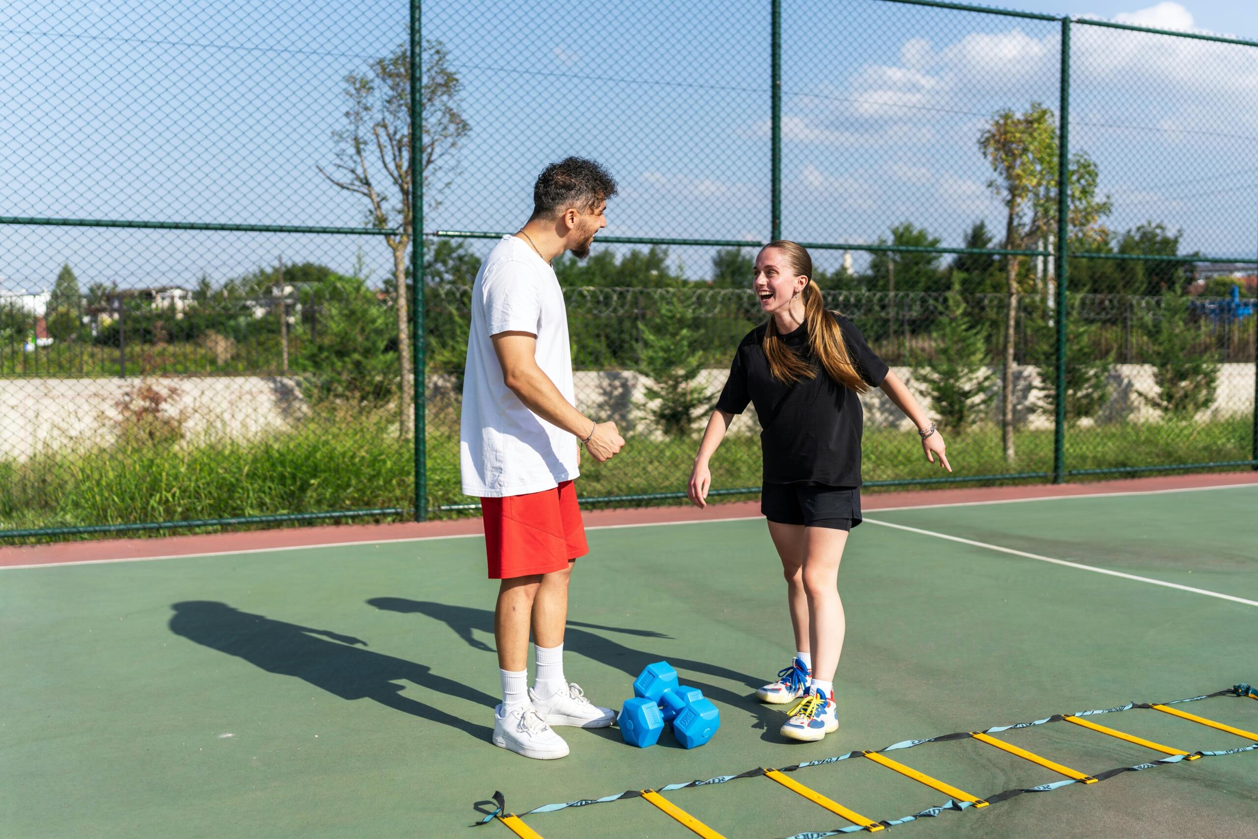 Προπονητής καθοδηγεί νεαρή αθλήτρια σε προπόνηση ταχύτητας σε γήπεδο.