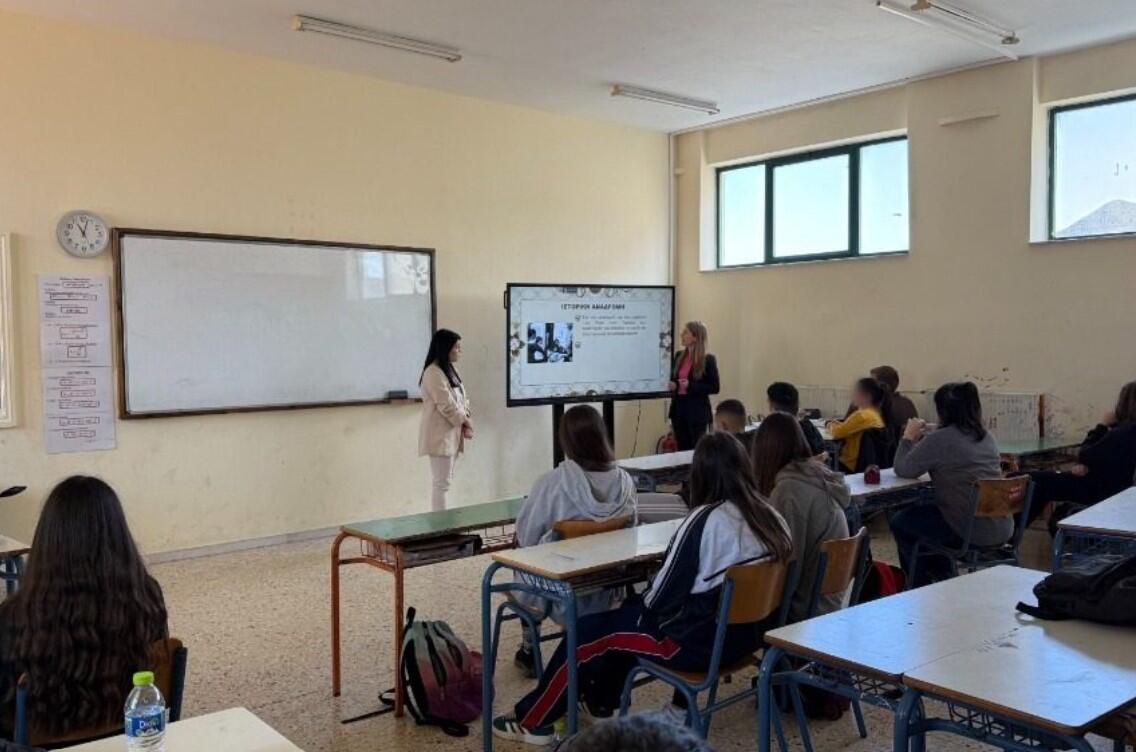 Εκπαιδευτική παρουσίαση σε σχολική τάξη, με ομιλήτριες μπροστά σε μαθητές και διαδραστικό πίνακα.